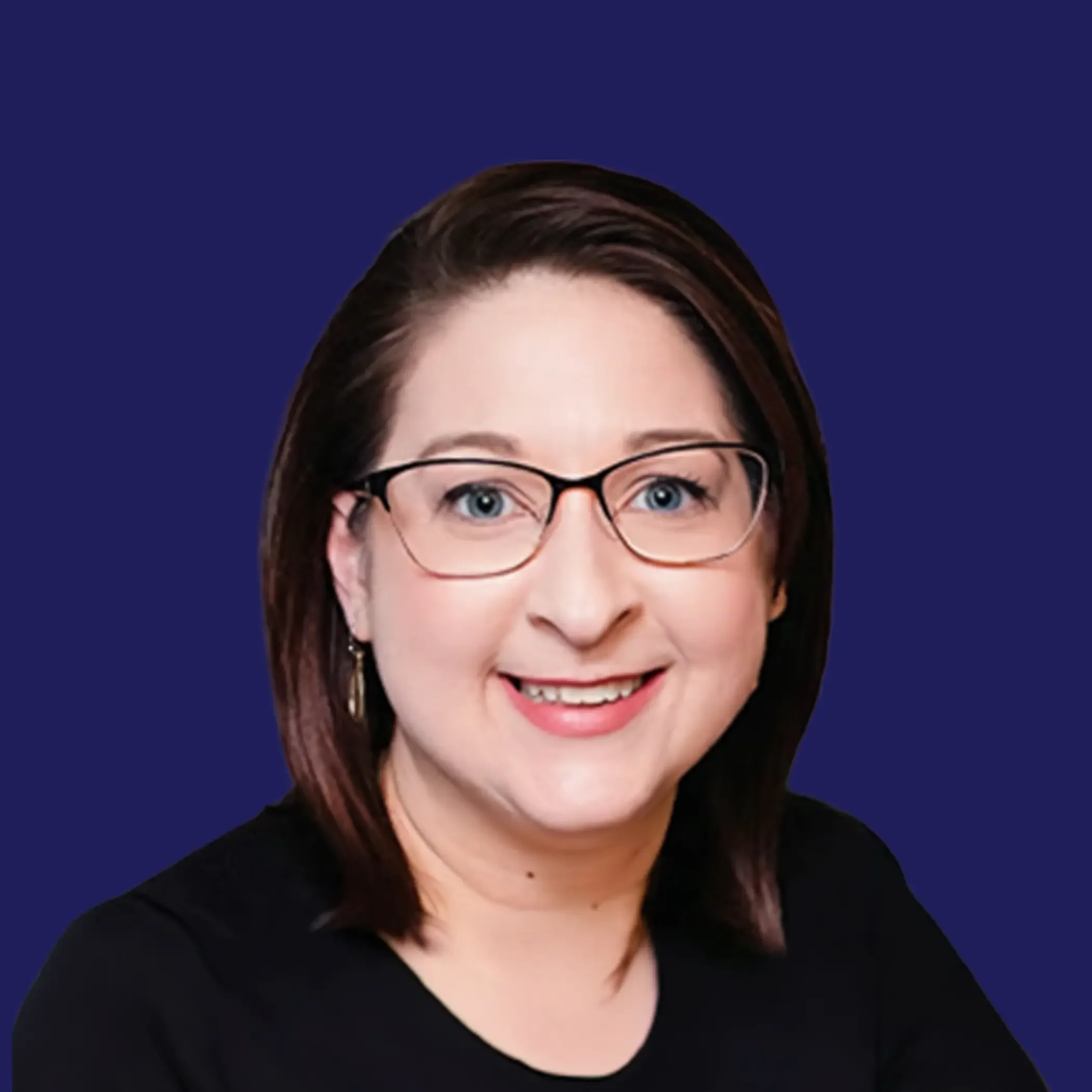 A woman with shoulder-length dark hair, glasses, and earrings, smiling in front of a neutral background.