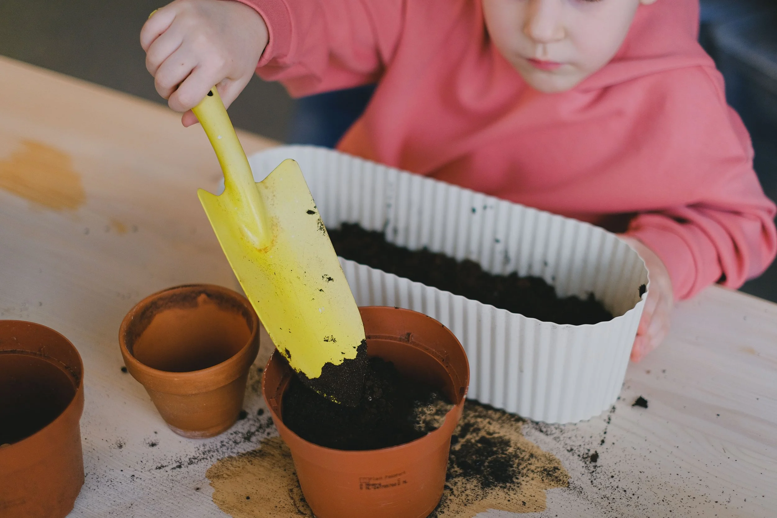 a child scooping dirt with a yellow trowel