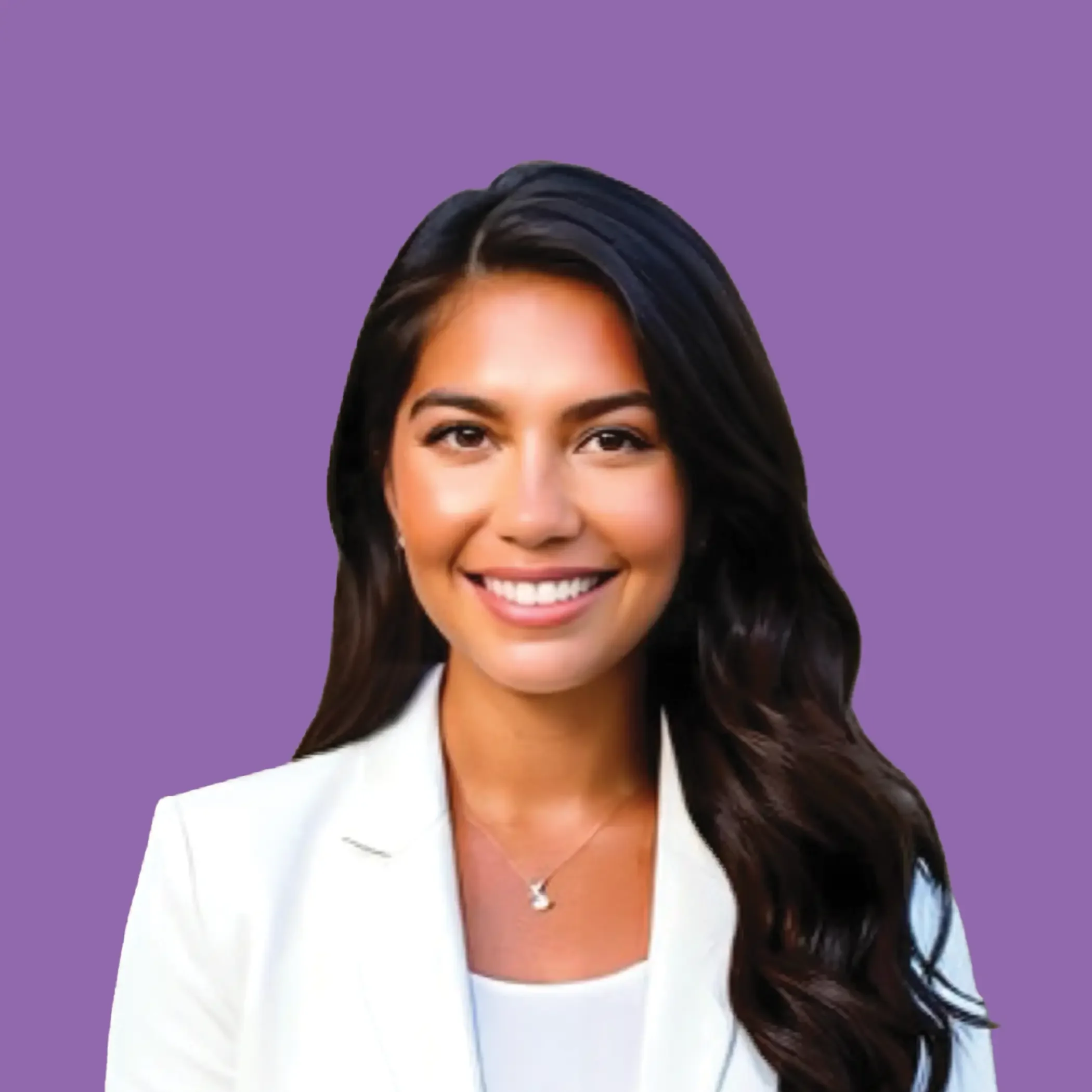 A woman with long dark hair, smiling, wearing a white blazer and a necklace, standing against a beige background.