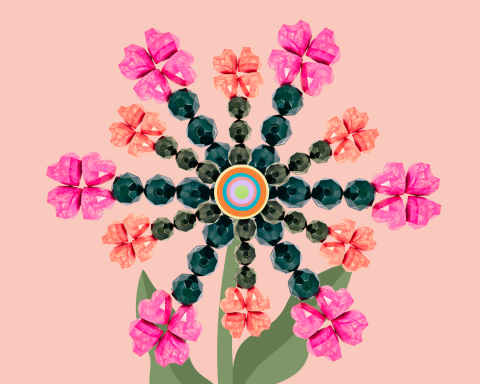 A colorful beaded bonbon flower with pink and orange petals with green beaded leaves on a light pink background.