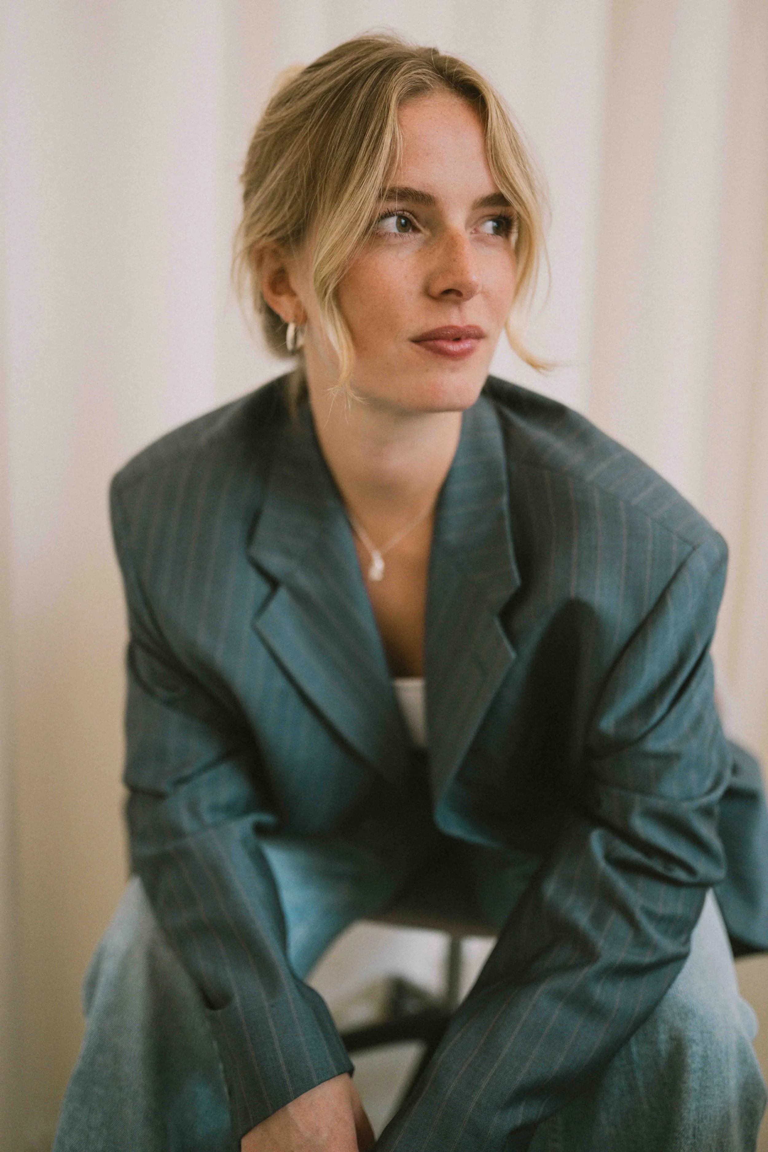 Nahaufnahme von Caro Nowak im grauen Blazer, zur Seite blickend