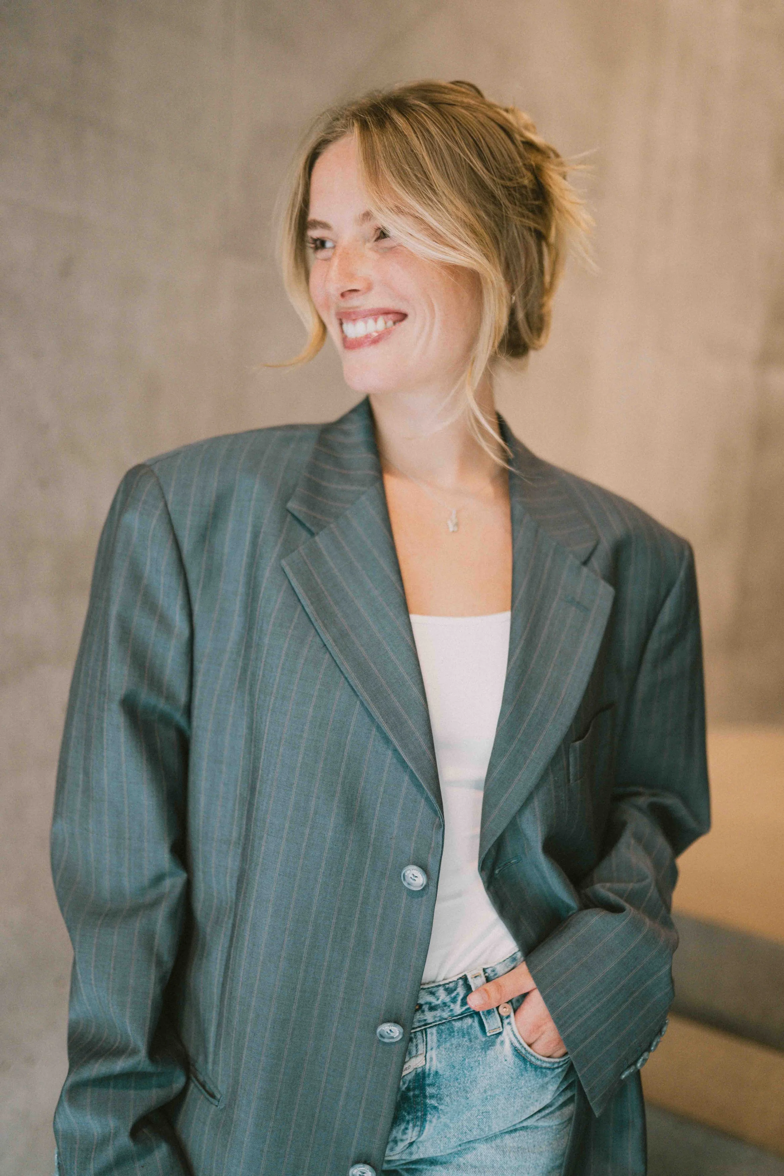 Caro Nowak lächelnd in grauem Nadelstreifen-Blazer