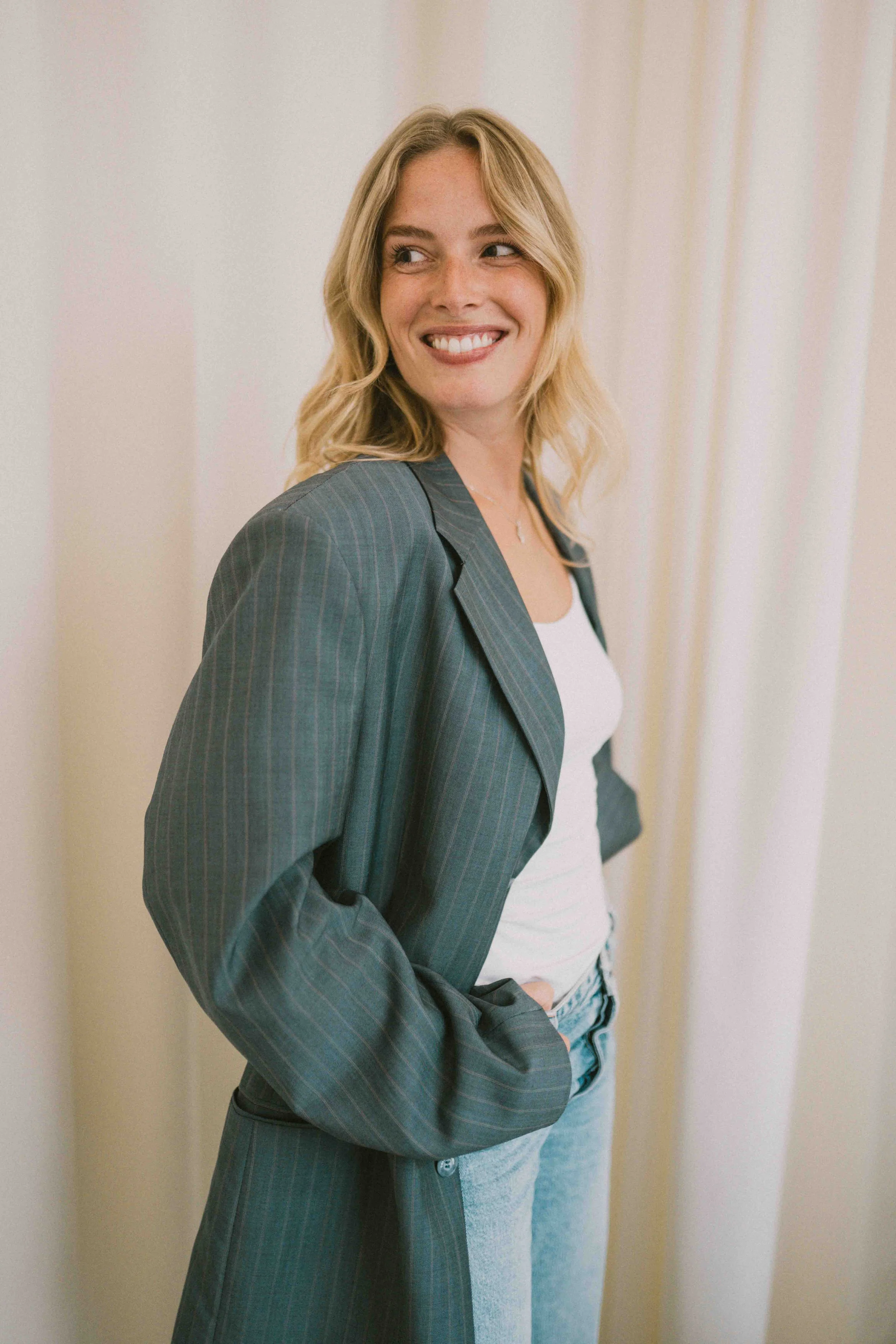 Caro Nowak lächelnd, Hände in den Taschen des Blazers