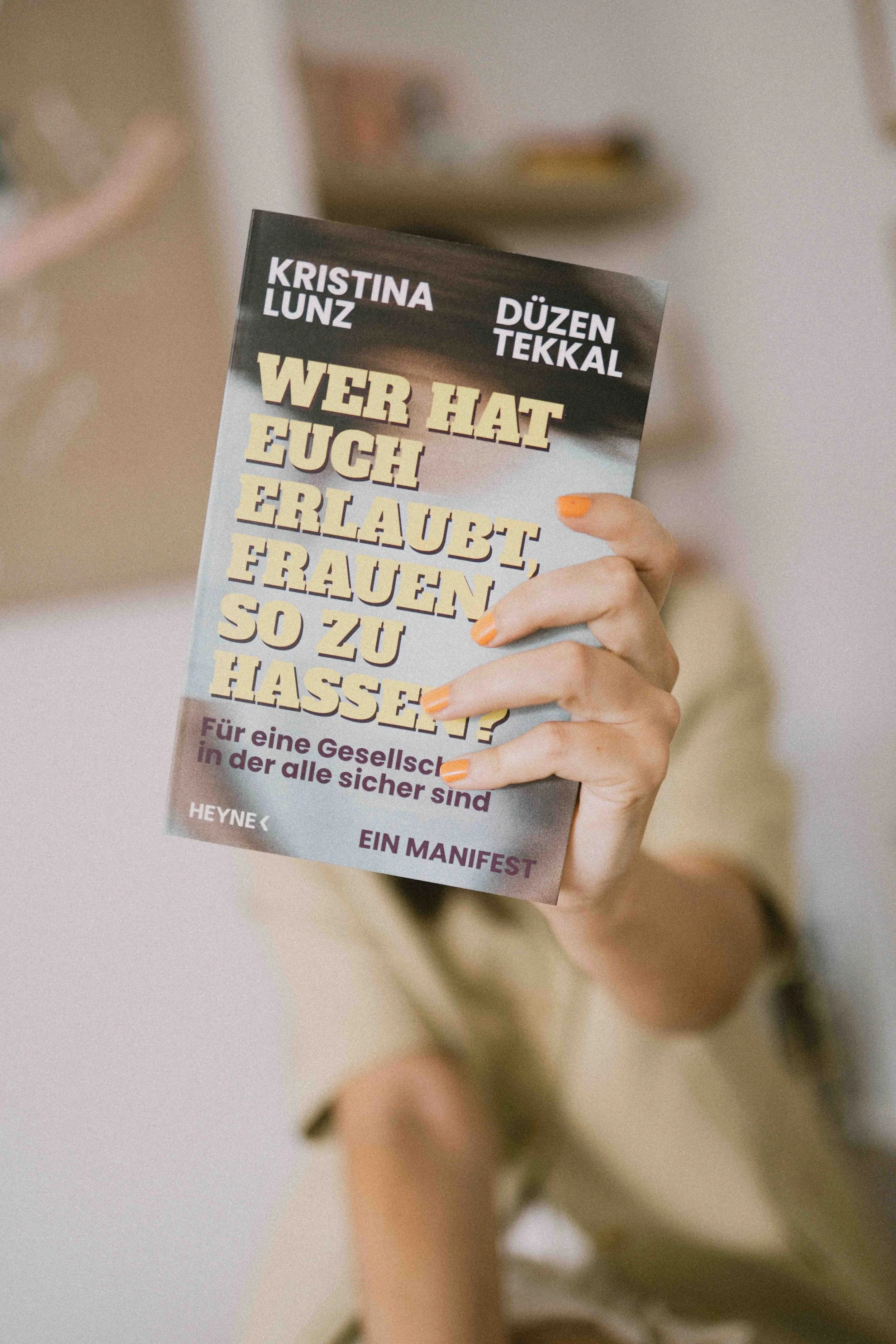 Nahaufnahme einer Hand, die das Buchcover „Wer hat euch erlaubt, Frauen so zu hassen?" hält
