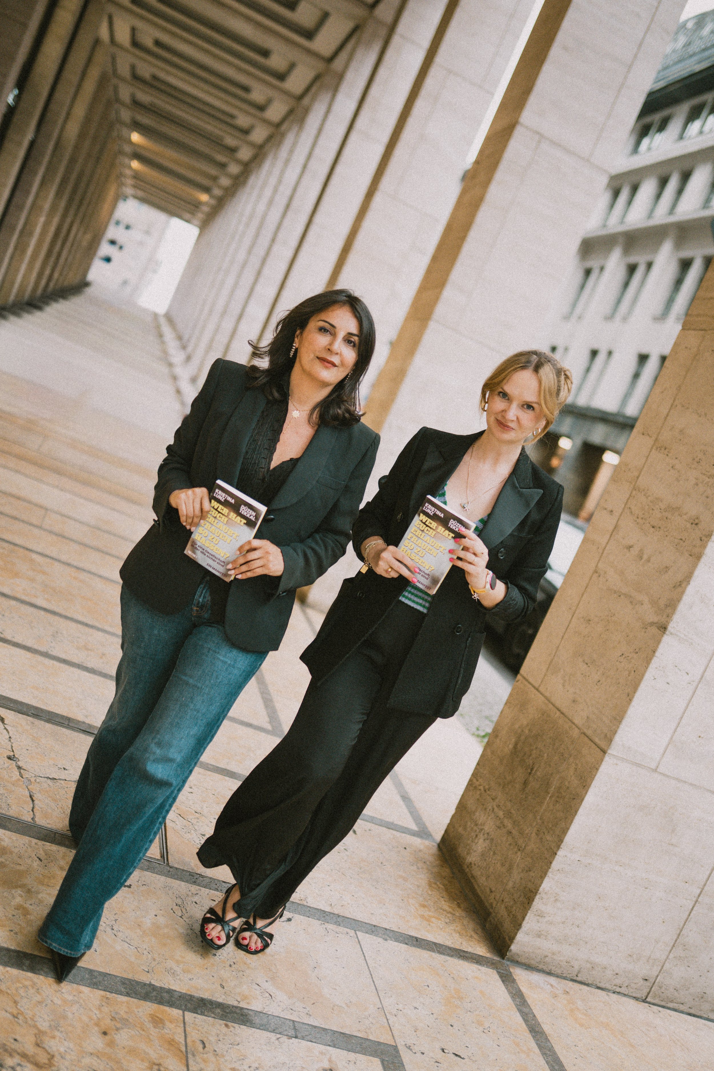 Kristina Lunz und Düzen Tekkal in grünen Blazern gehen gemeinsam, eine hält das Buch in der Hand