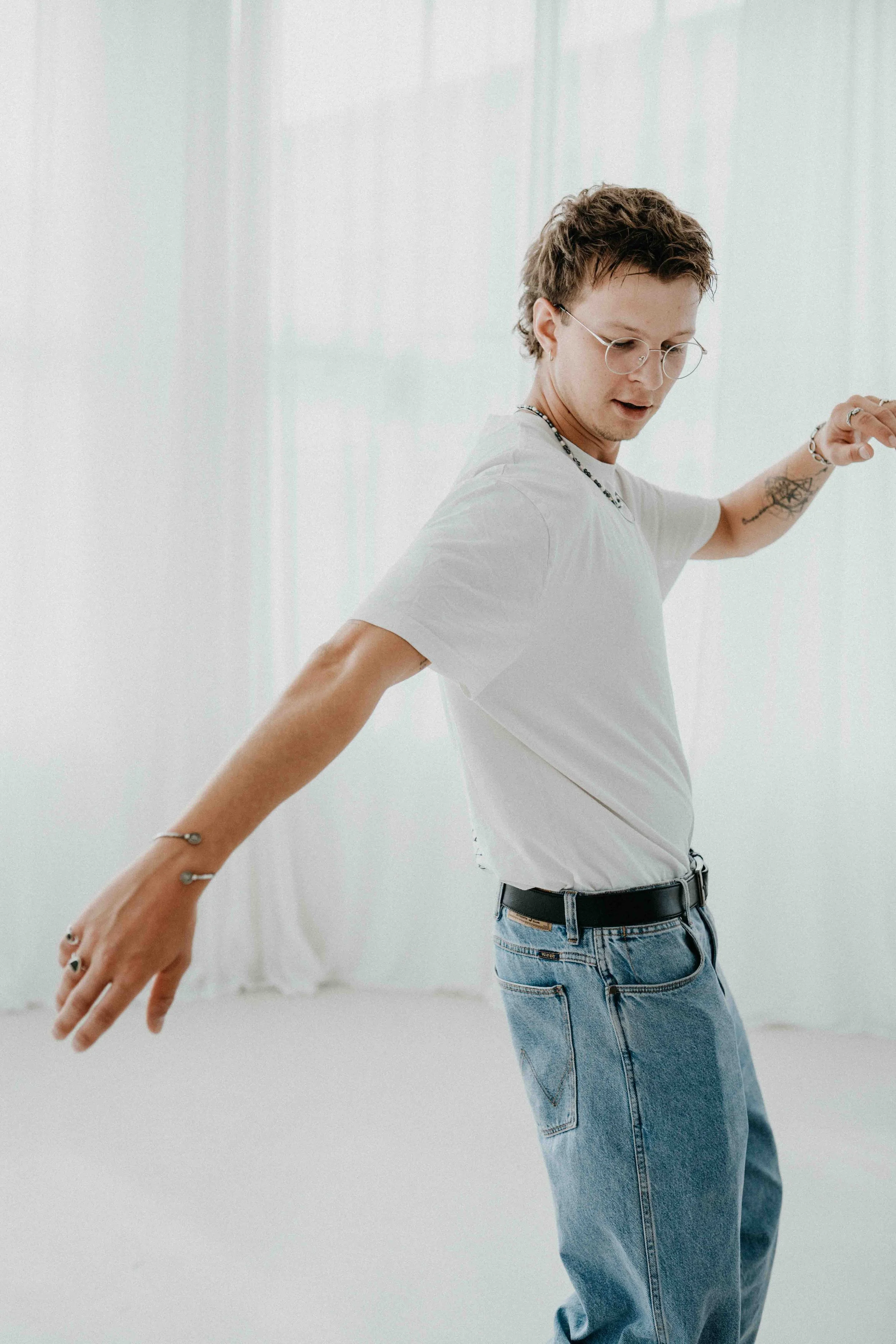 Mann in Bewegung mit ausgestrecktem Arm, weißes T-Shirt und Jeans