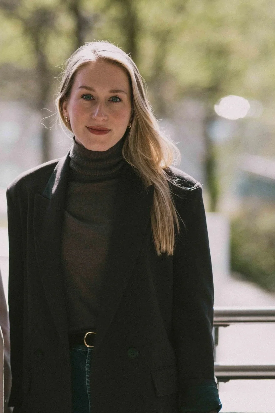 Blonde Frau in dunklem Mantel im Freien