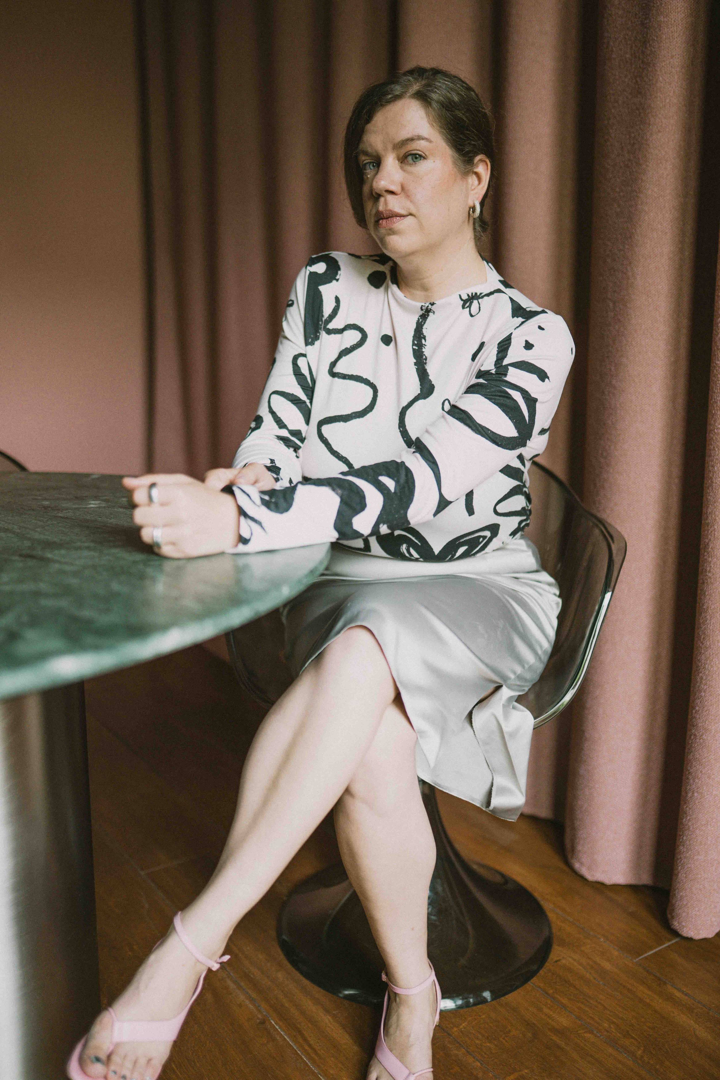 Jeannette Gusko sitzend auf einem Tisch, im gemusterten Kleid
