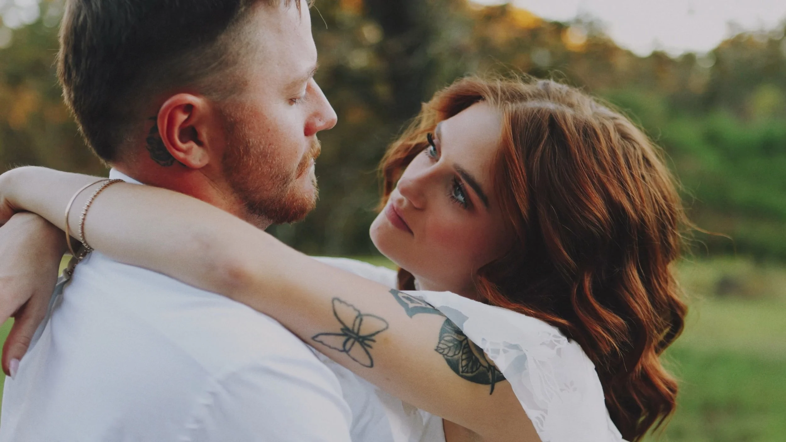 Engaged couple with the womans arms around the mans neck, staring into each others eyes.