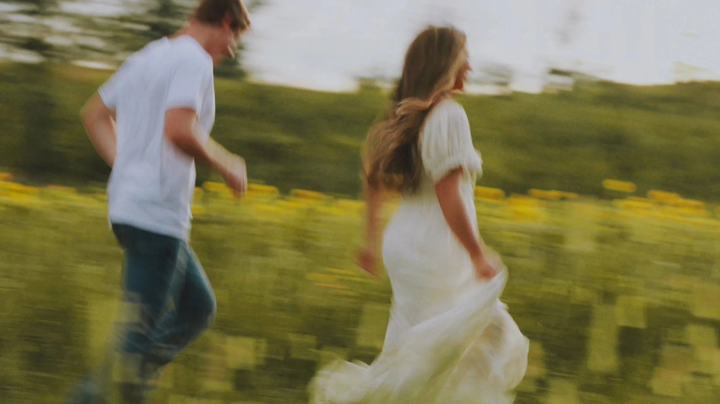 Engaged couple running through a yellow flower field in North Mississippi.