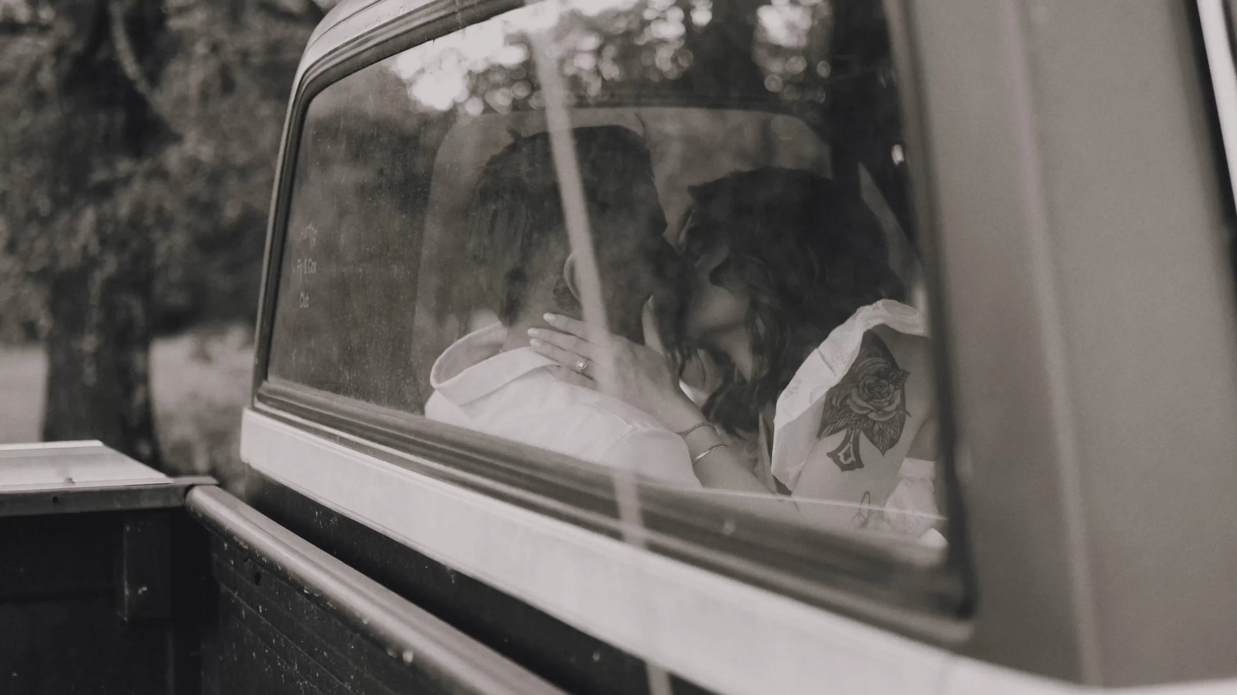 Engaged couple sharing a kiss through the back window of a vintage truck.