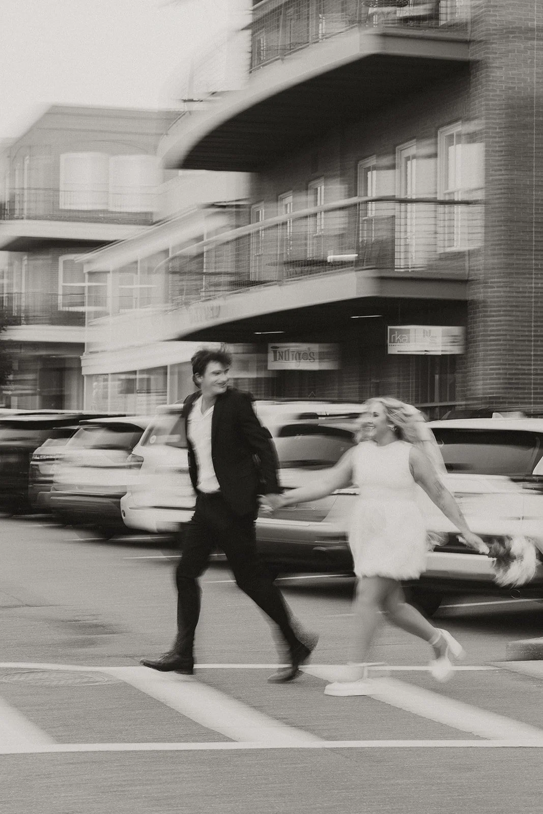 Black and white image of a couple hand in hand running across the street in Oxford, Mississippi.
