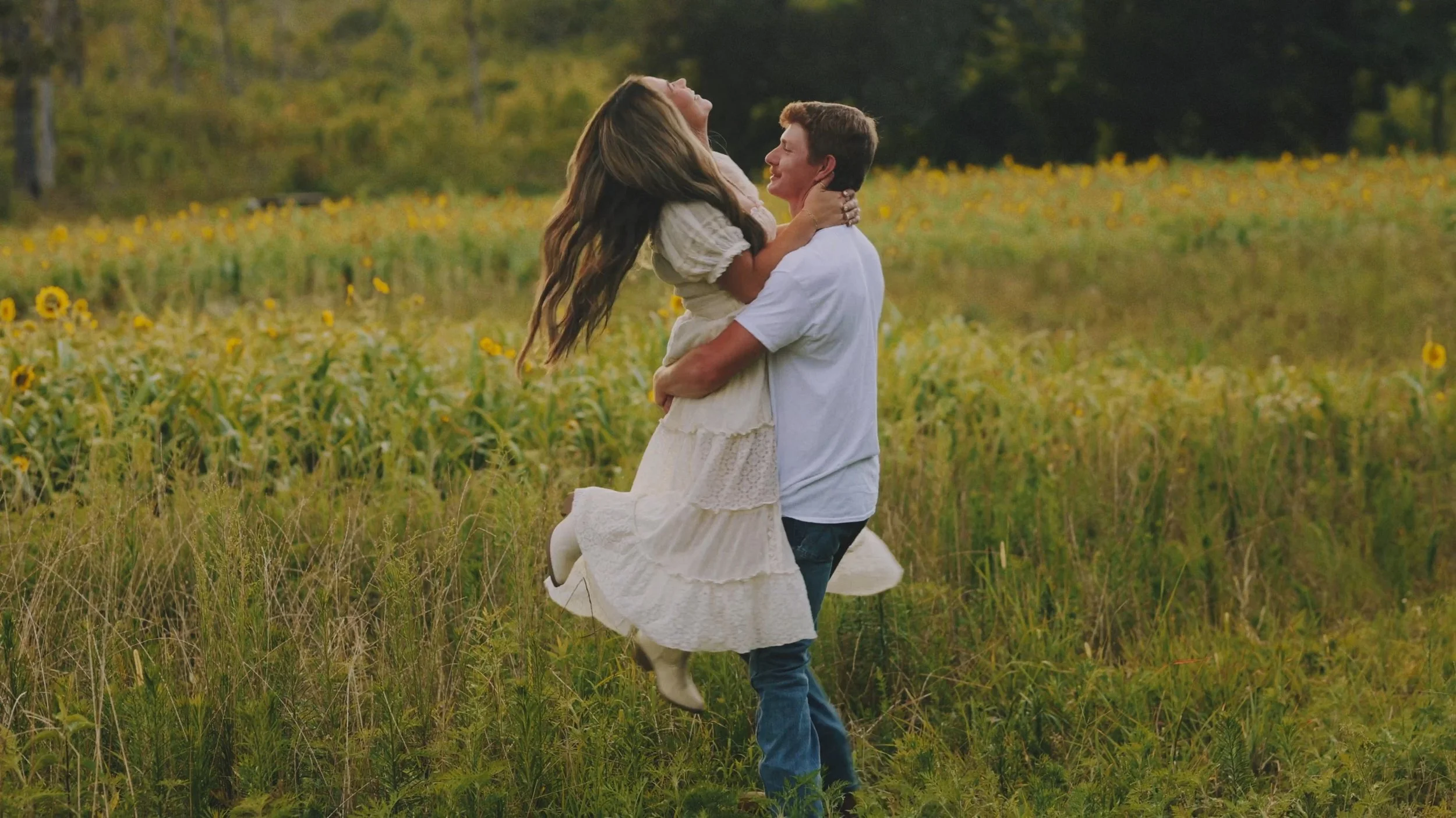 A man picking up his fiance and spinning her in a circle in a flower field in North Mississippi