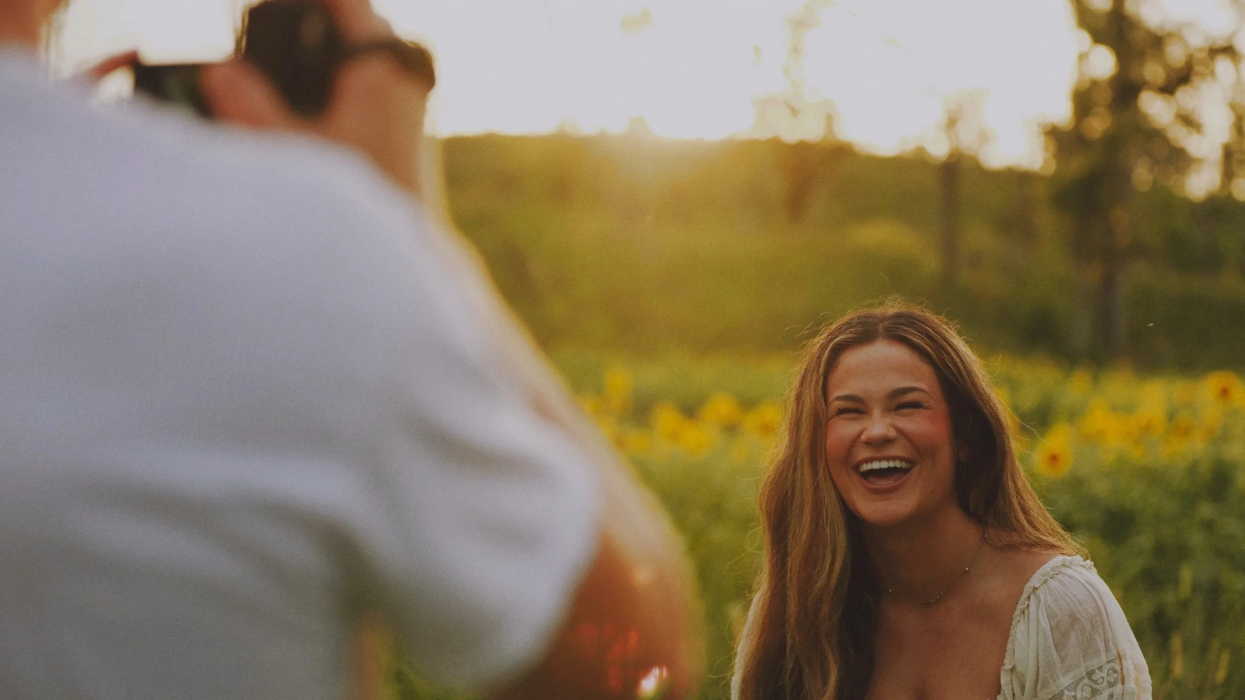 A woman's fiance videoing her laughing with a camcorder.
