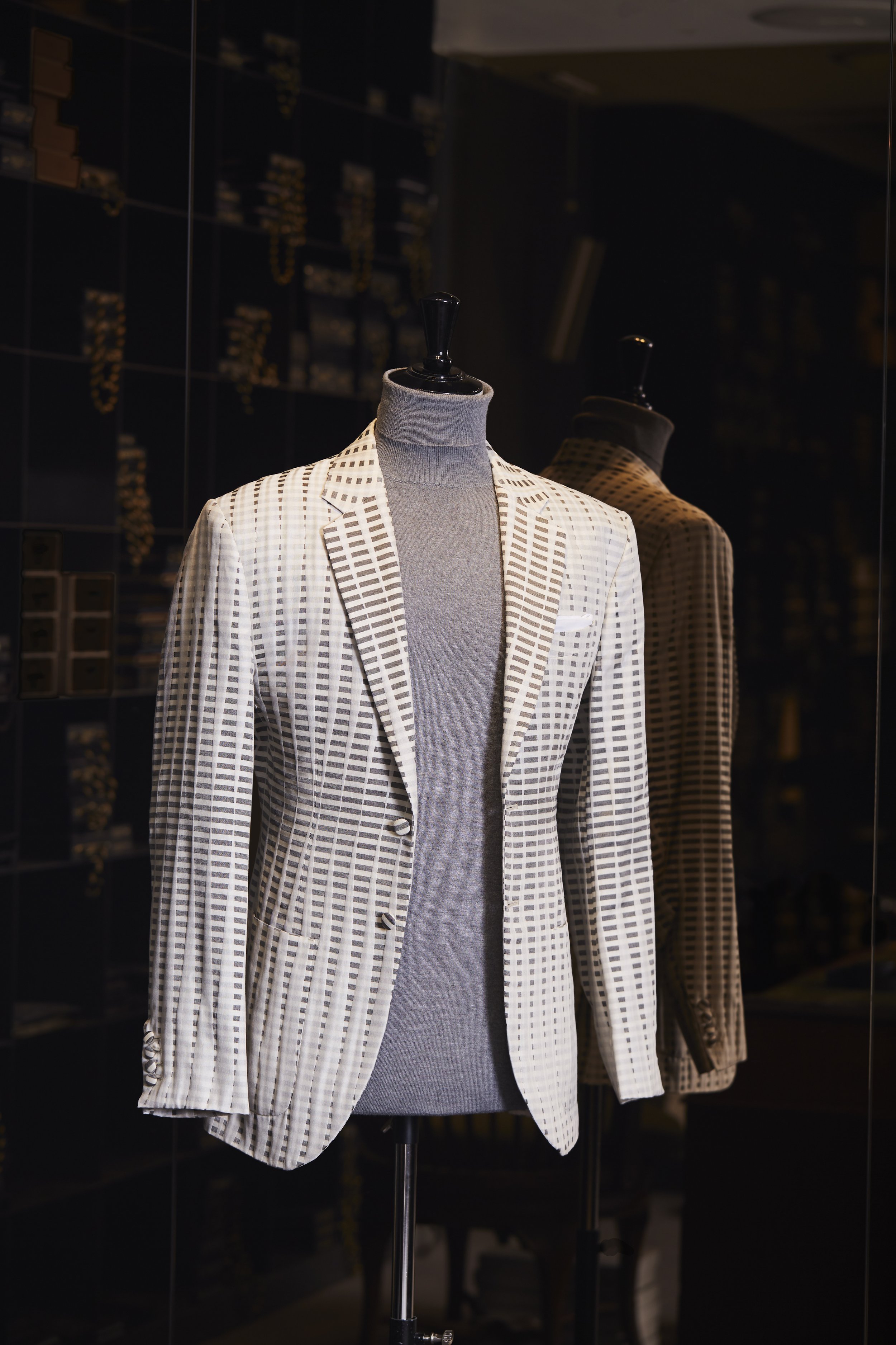 Mannequin wearing a checkered blazer and turtleneck sweater inside a clothing store.