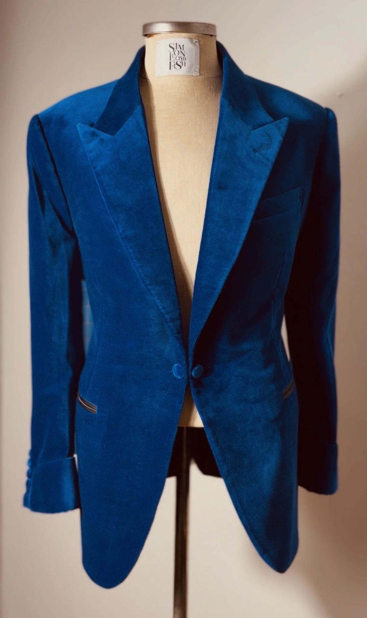 A blue blazer jacket displayed on a beige mannequin, with a label on the neck reading 'FASHION LONDON S'.
