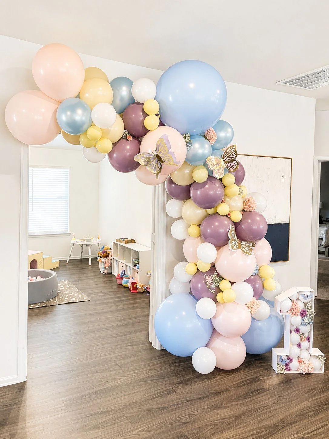 Colorful balloon arch with butterflies and flowers in a nursery or party room.