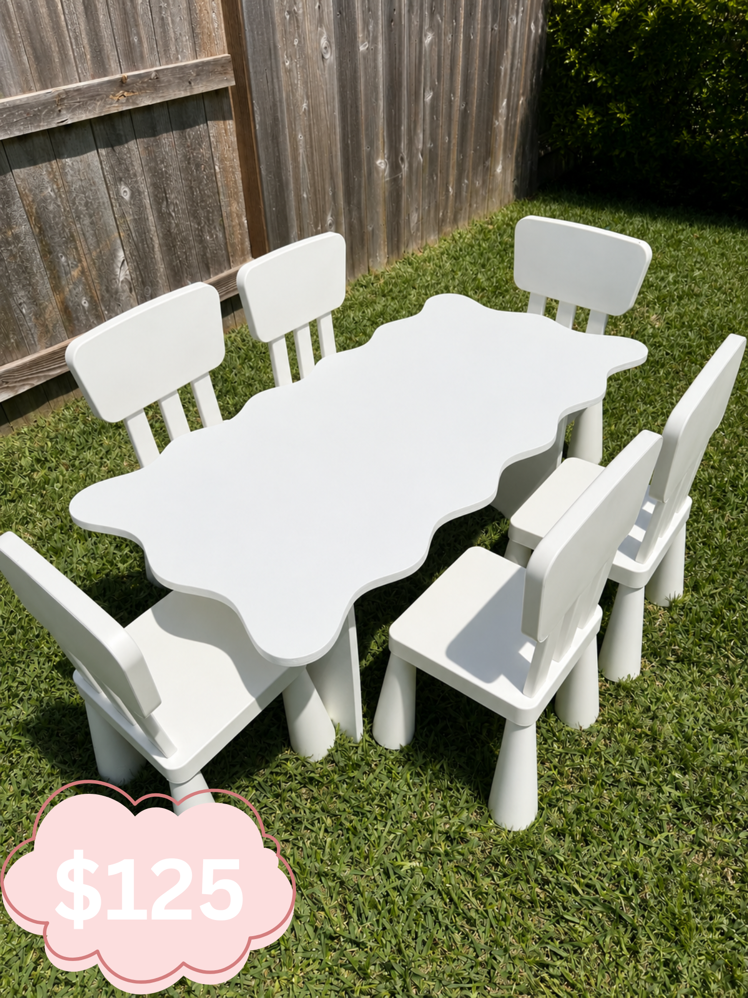 Outside scene showing a white plastic outdoor table and six matching chairs on grass, with a wooden fence and a bush in the background, and a pink price tag graphic displaying '$125'.