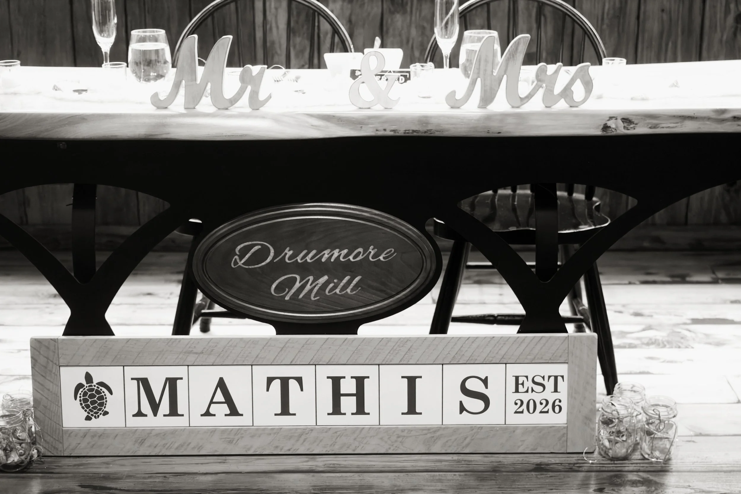 A table decorated for Mother's Day with a sign saying 'Mom & Mums' and a display labeled 'Mathis' with some jars of buttons or small items.