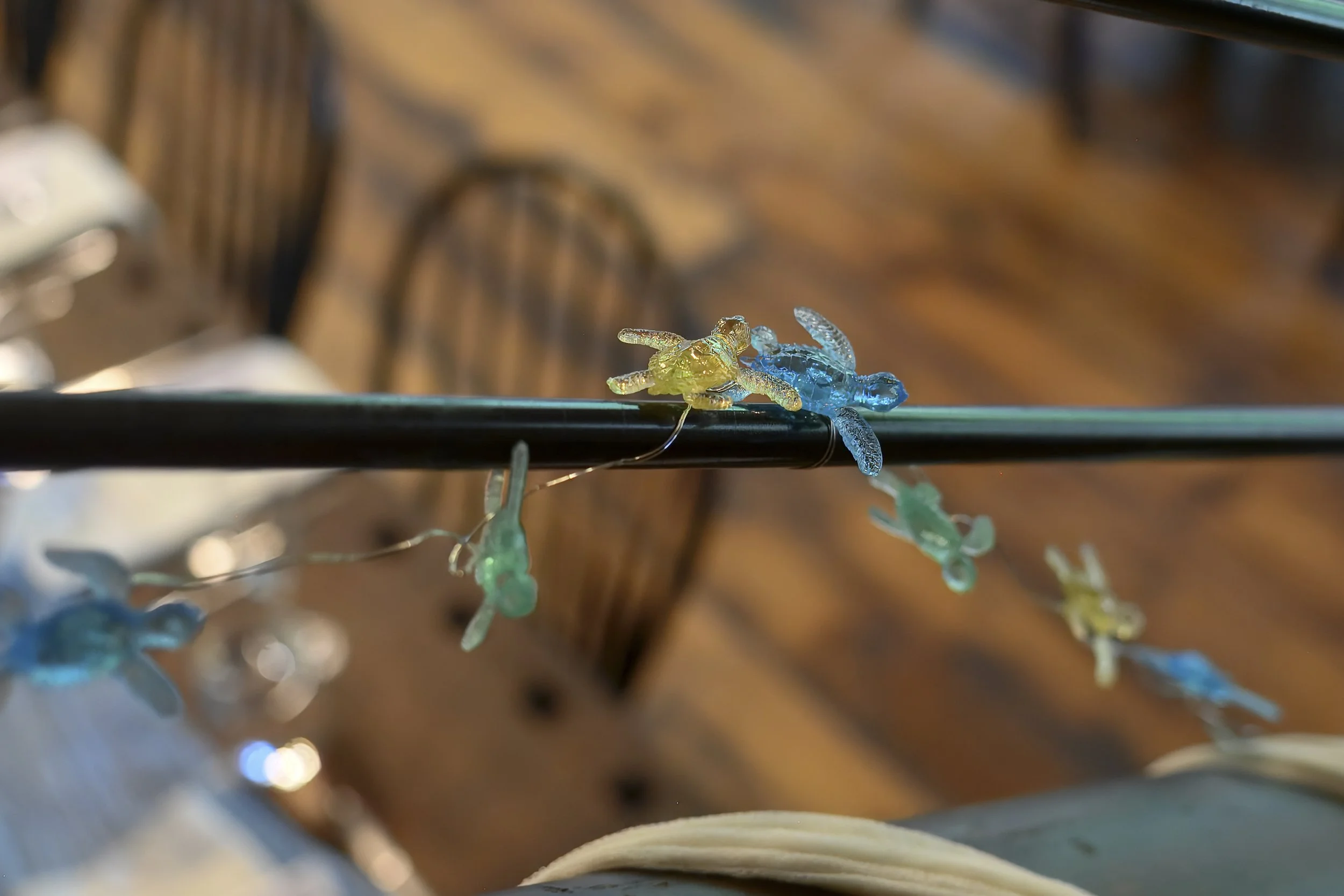 Close-up of a string of decorative dragonfly-shaped lights, with one yellow and one blue dragonfly, hanging in front of a blurred background.