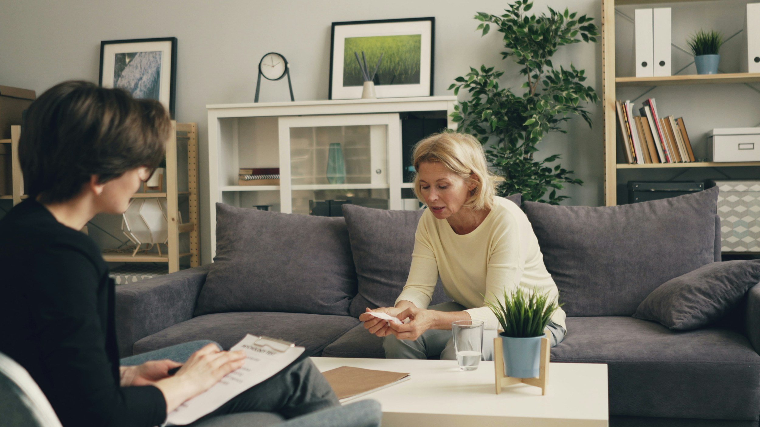 a woman holding a tissue and talking to a therapist while sitting on a couch