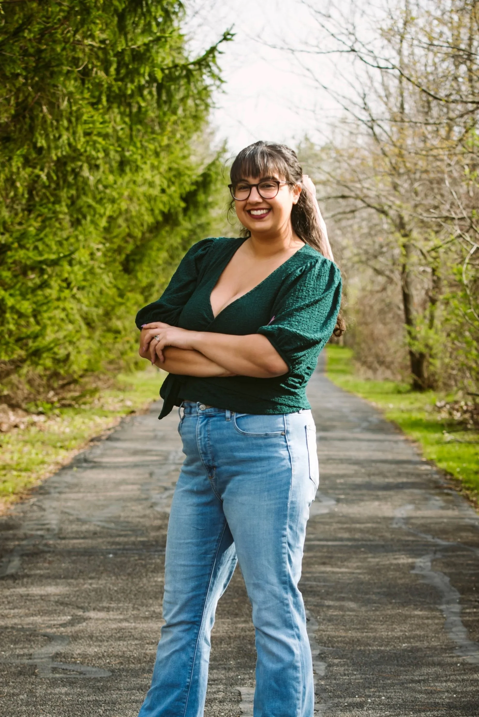 a woman with hispanic features smiling into the camera in an outdoor forest landscape