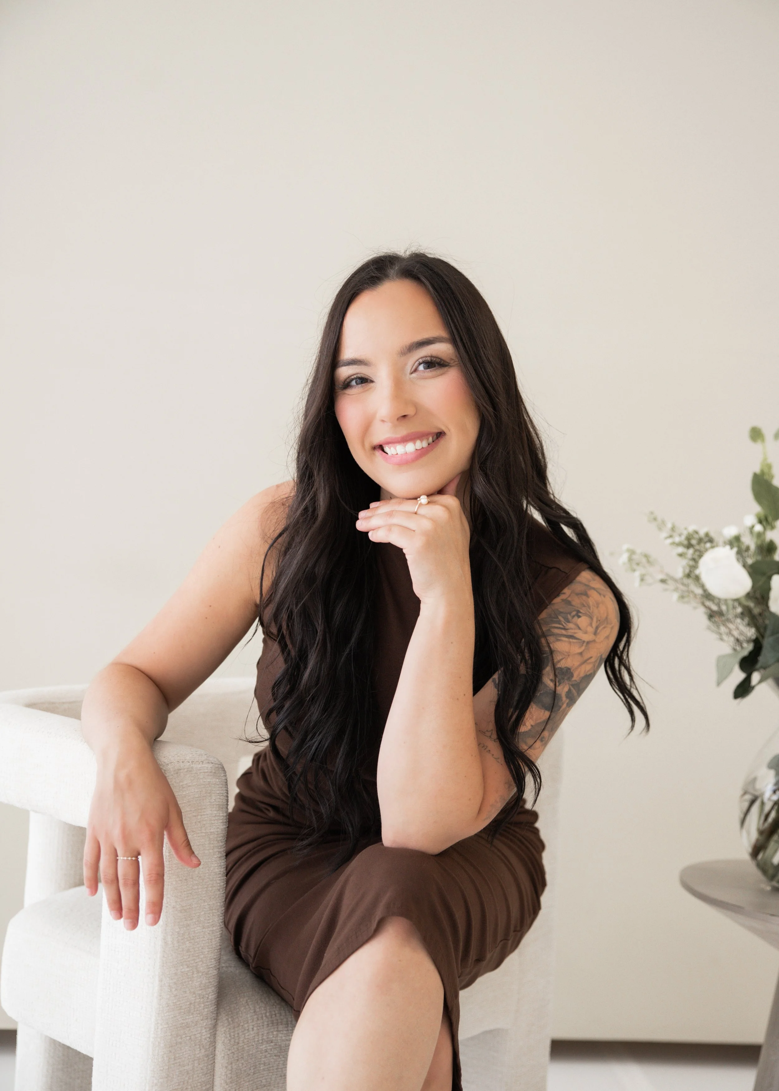 a woman with dark hair sitting on a chair and smiling