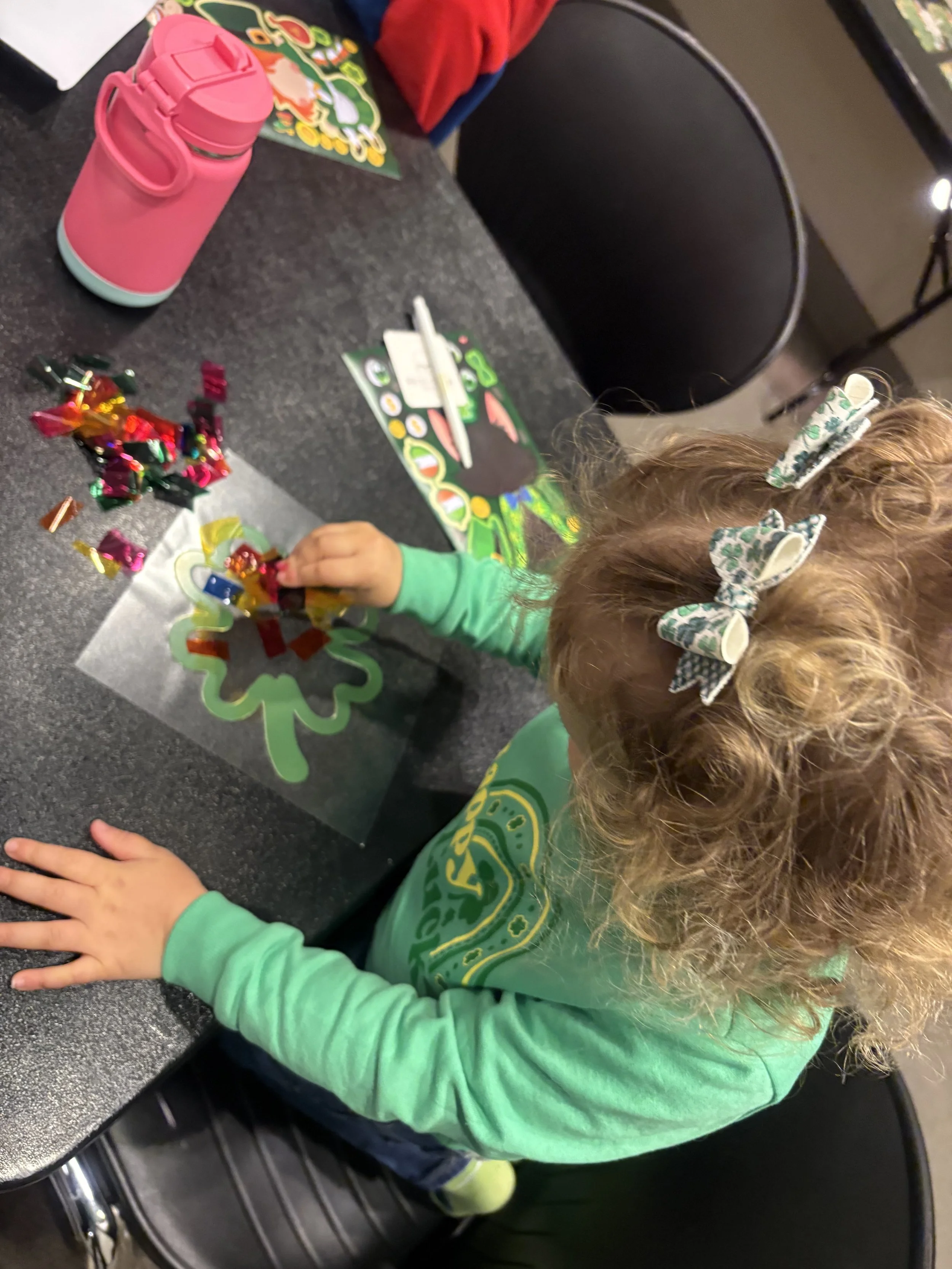 a toddler wearing green working on a shamrock St. Patricks Day craft