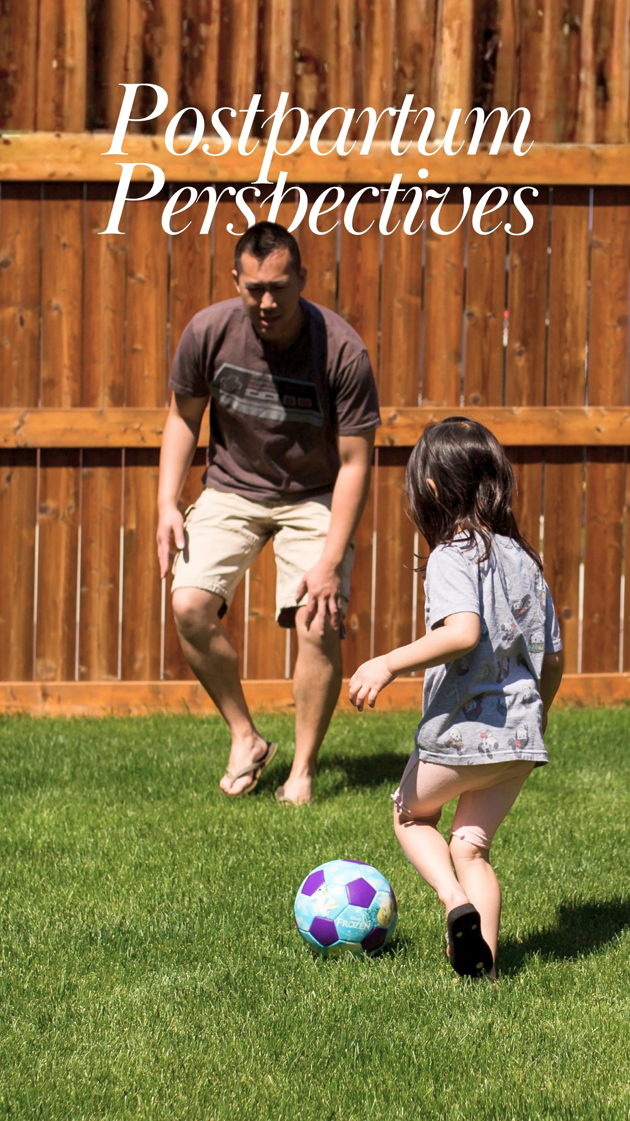 A father playing soccer with his daughter in the fenced in backyard.