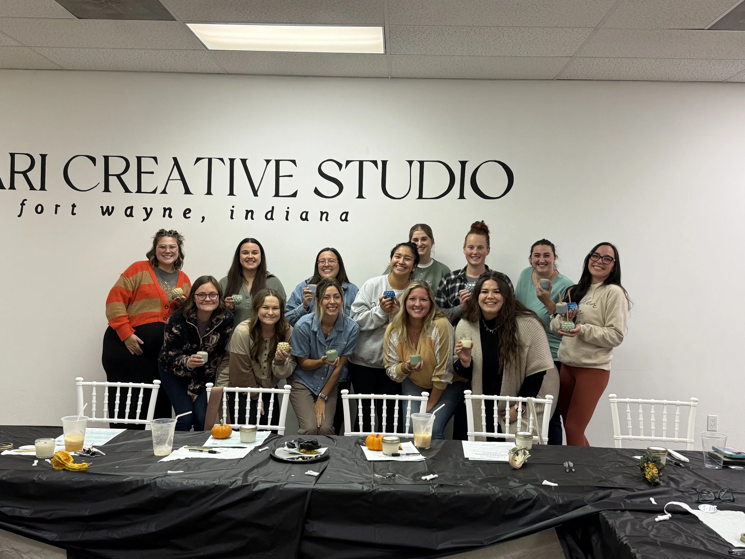 a group of 15 moms holding candles in front of a table