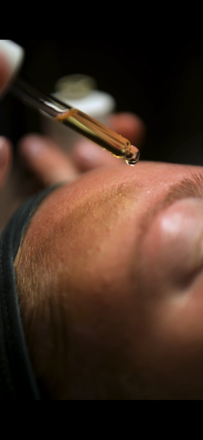 En person får en ansiktsbehandling med en pipett som applicerar en vätska på huden.