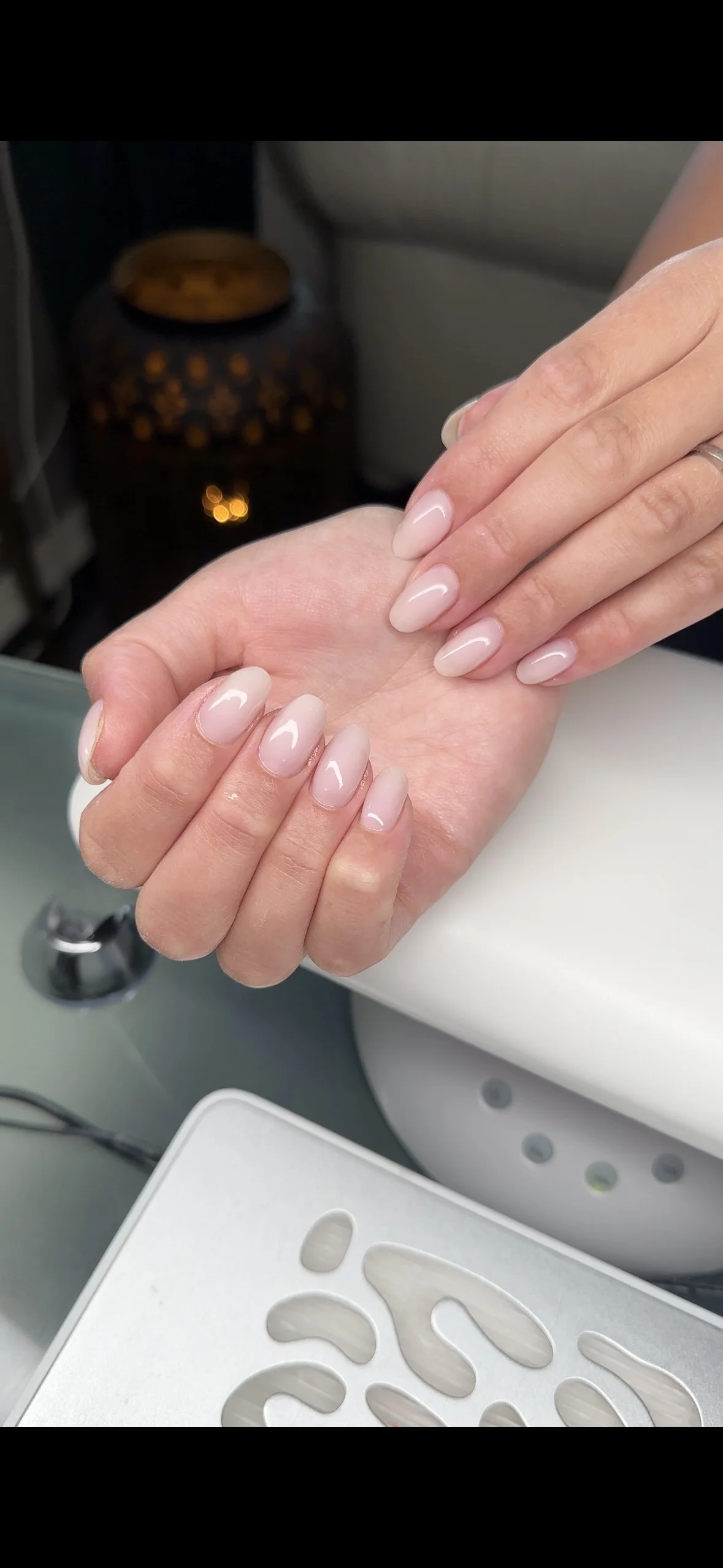 Nyanserade, välvårdade naglar med ljus rosa gel och högglansiga ytor, där en person får sina naglar fixade på ett nagelsalongsrum.