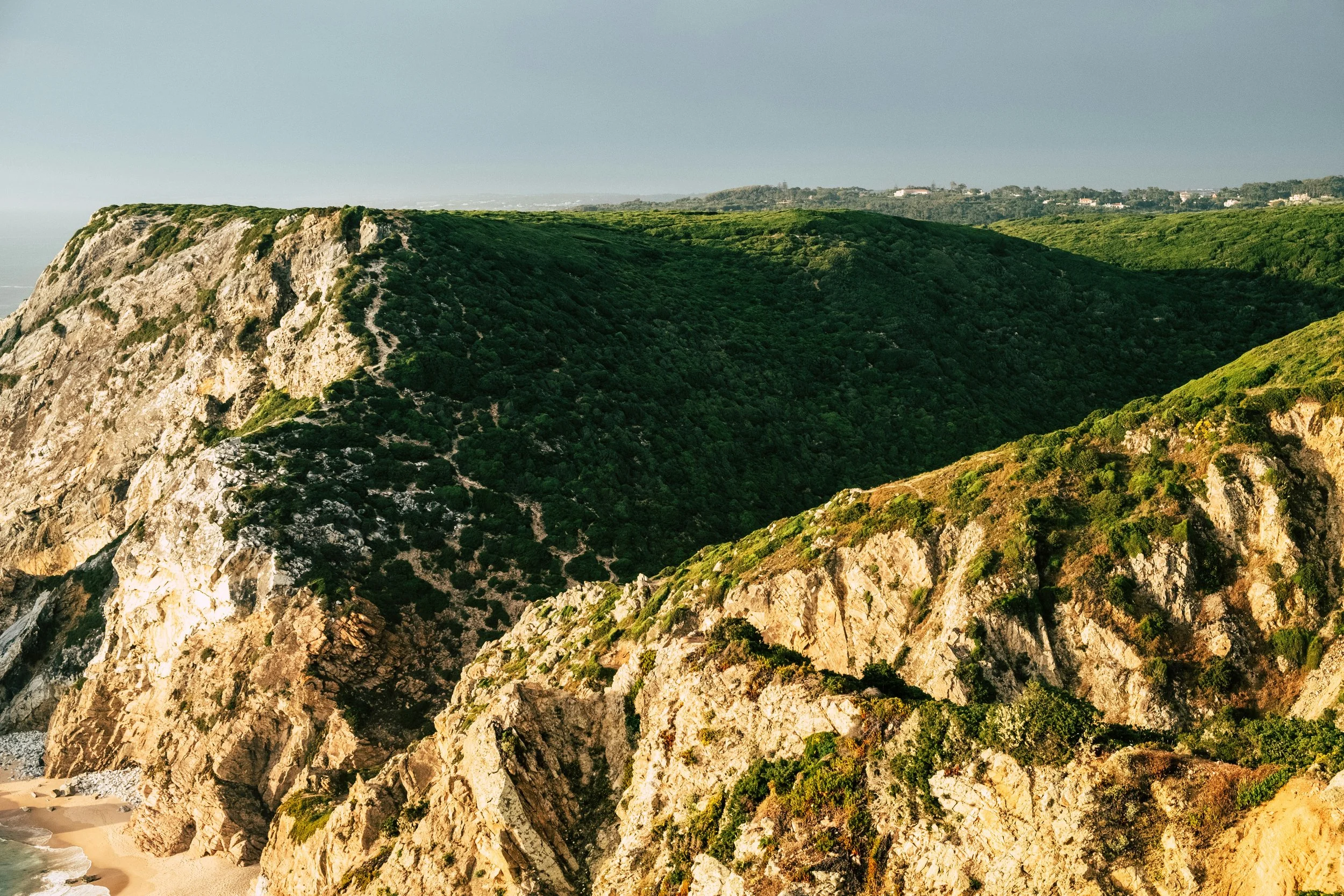 Cliffs com vegetação verde cobrem uma paisagem natural junto ao mar.