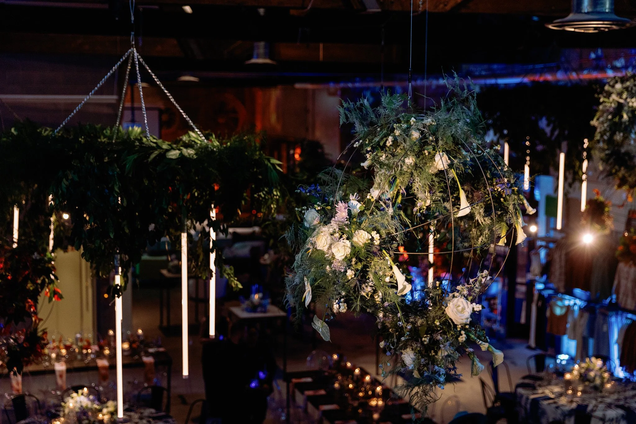 Hanging floral arrangement with white flowers and greenery in a dimly lit indoor setting.