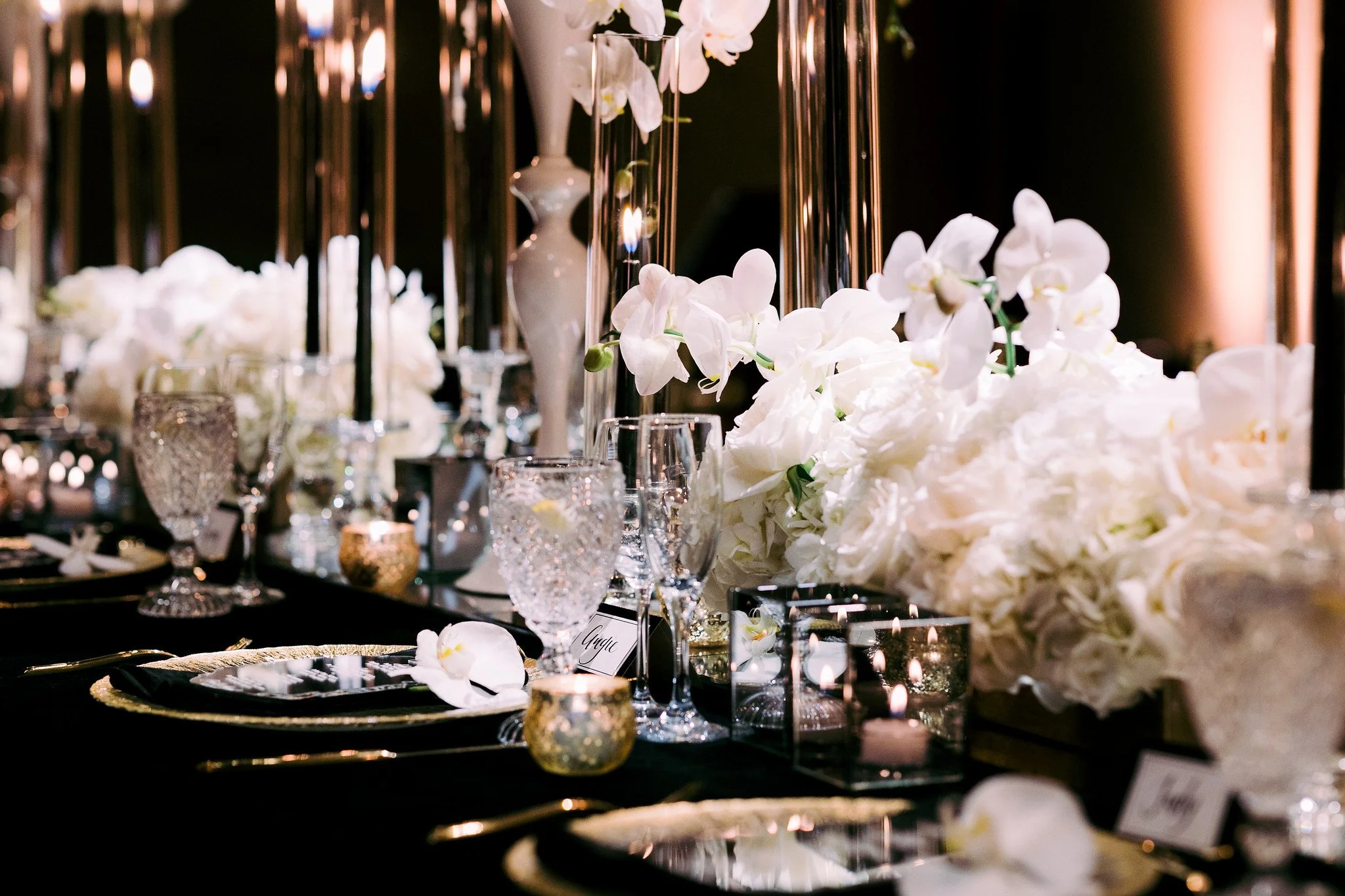 A table decorated with white flowers, candles, and glassware at an elegant event or wedding reception.