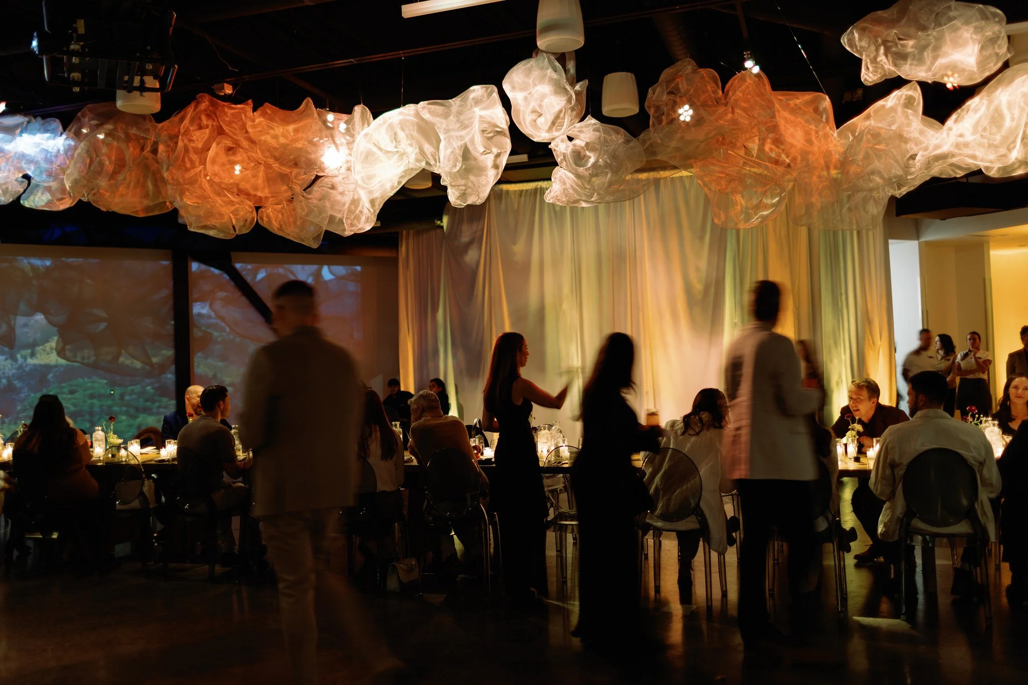 People dining at a restaurant with a large cloud-like light fixture hanging from the ceiling.