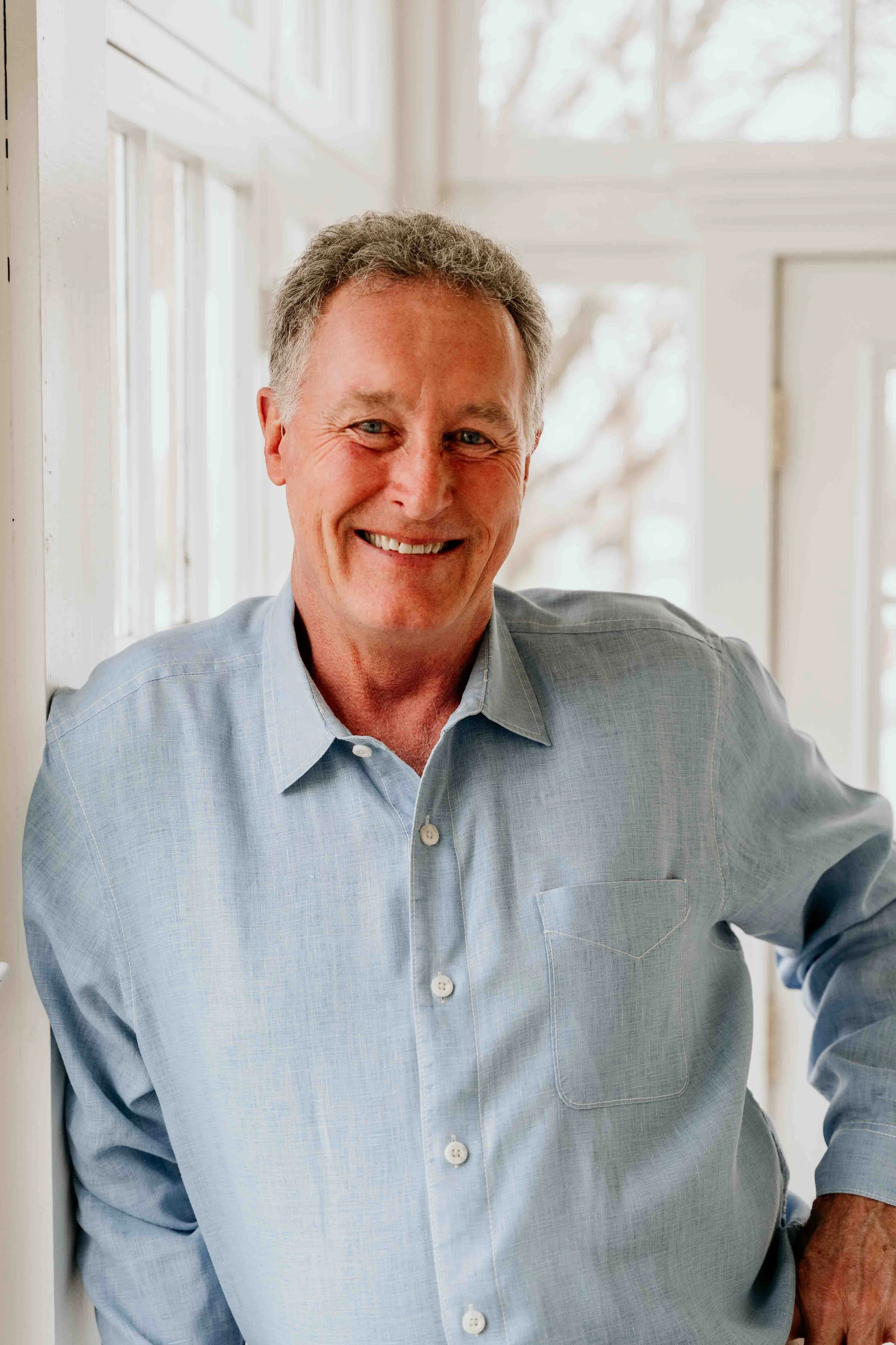 Winemaker & lavender artisan of Mahan Family Wines & Granite Ridge Vineyard. He is standing indoors near a window with natural light coming in, and there are trees visible outside.