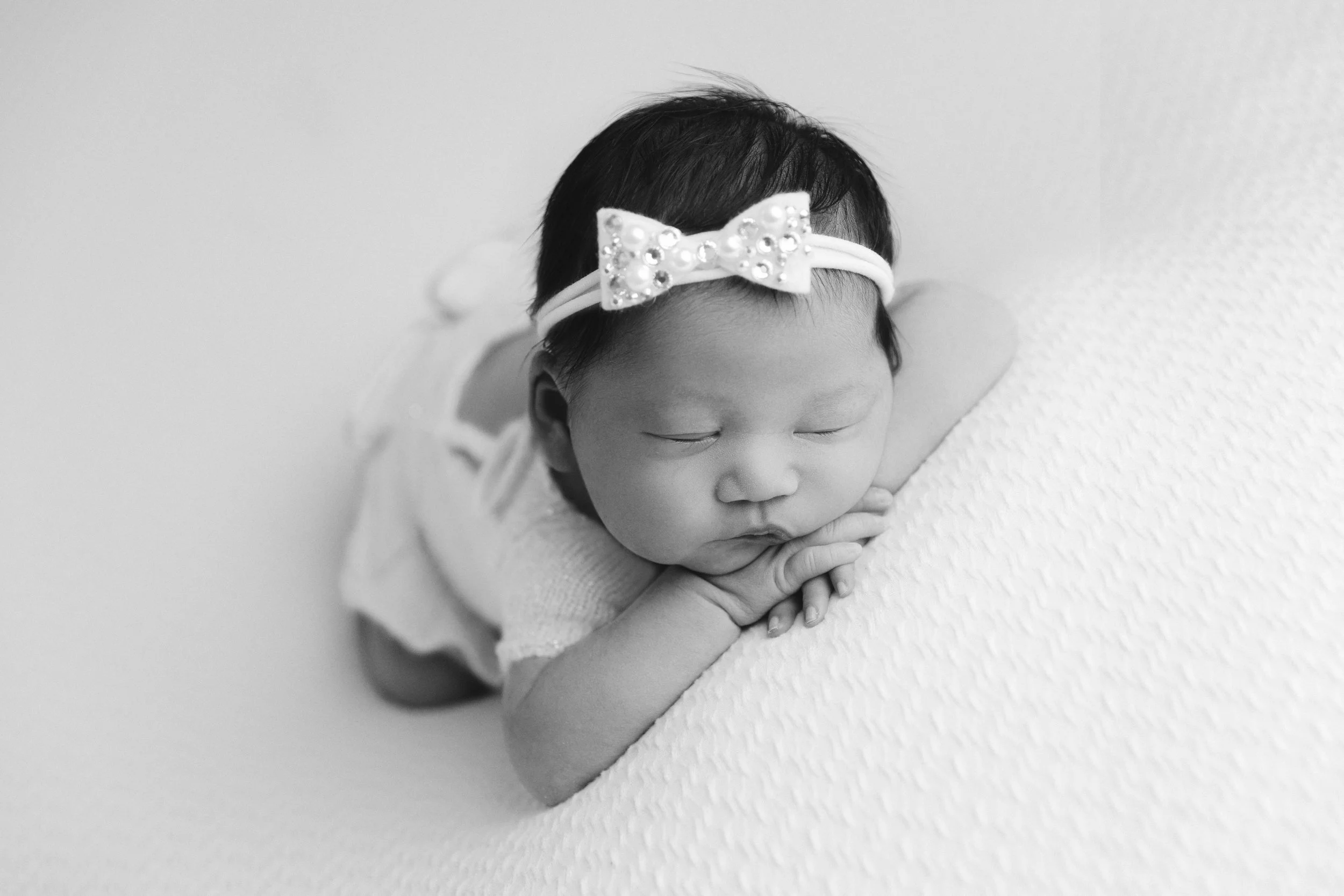 Sleeping newborn baby girl wearing a bow during a Southern California newborn photography session by Mariah Therese Photography, serving the Inland Empire, Orange County, and Los Angeles County.