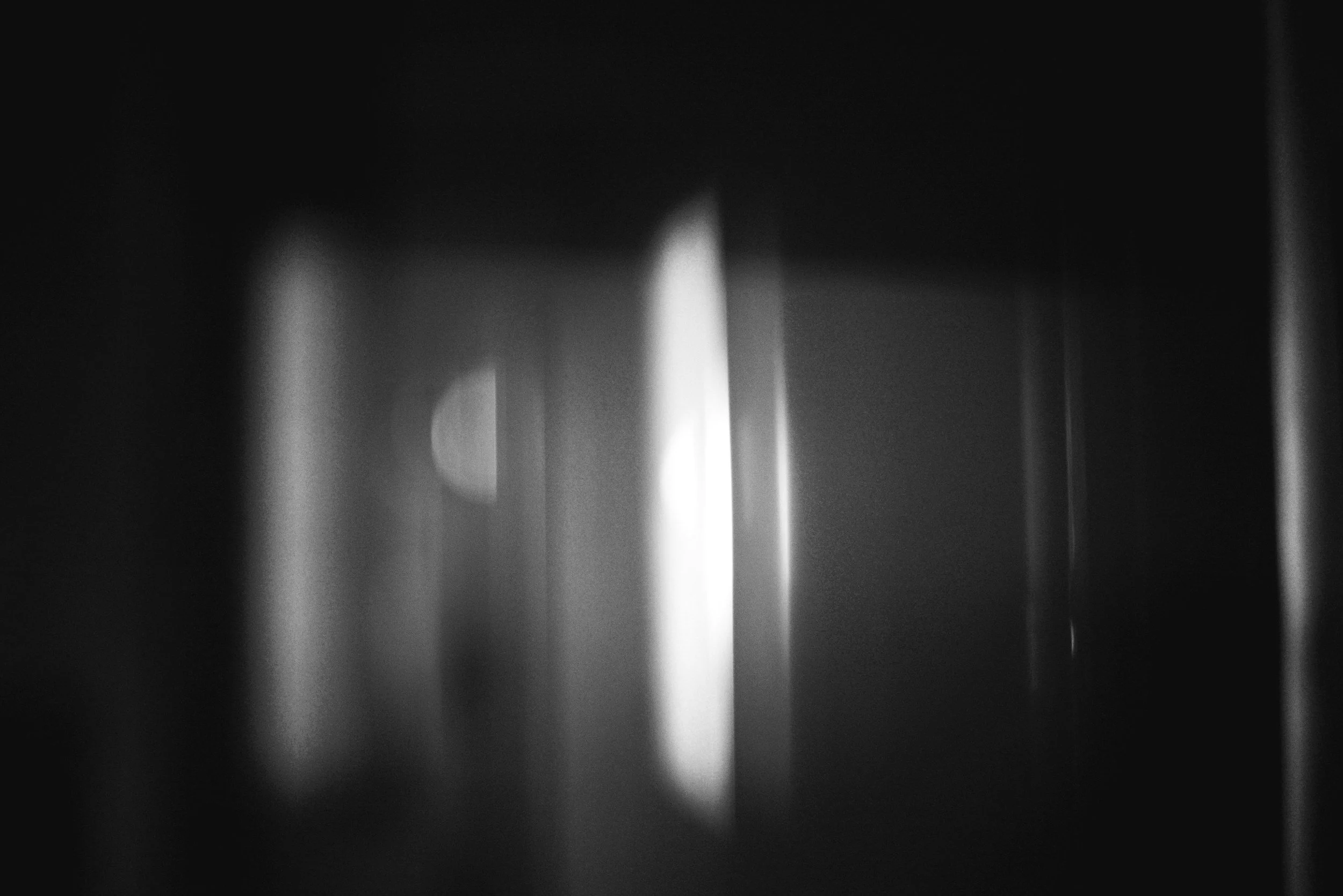 Abstract black and white photo with blurred vertical light streaks and bokeh effect.