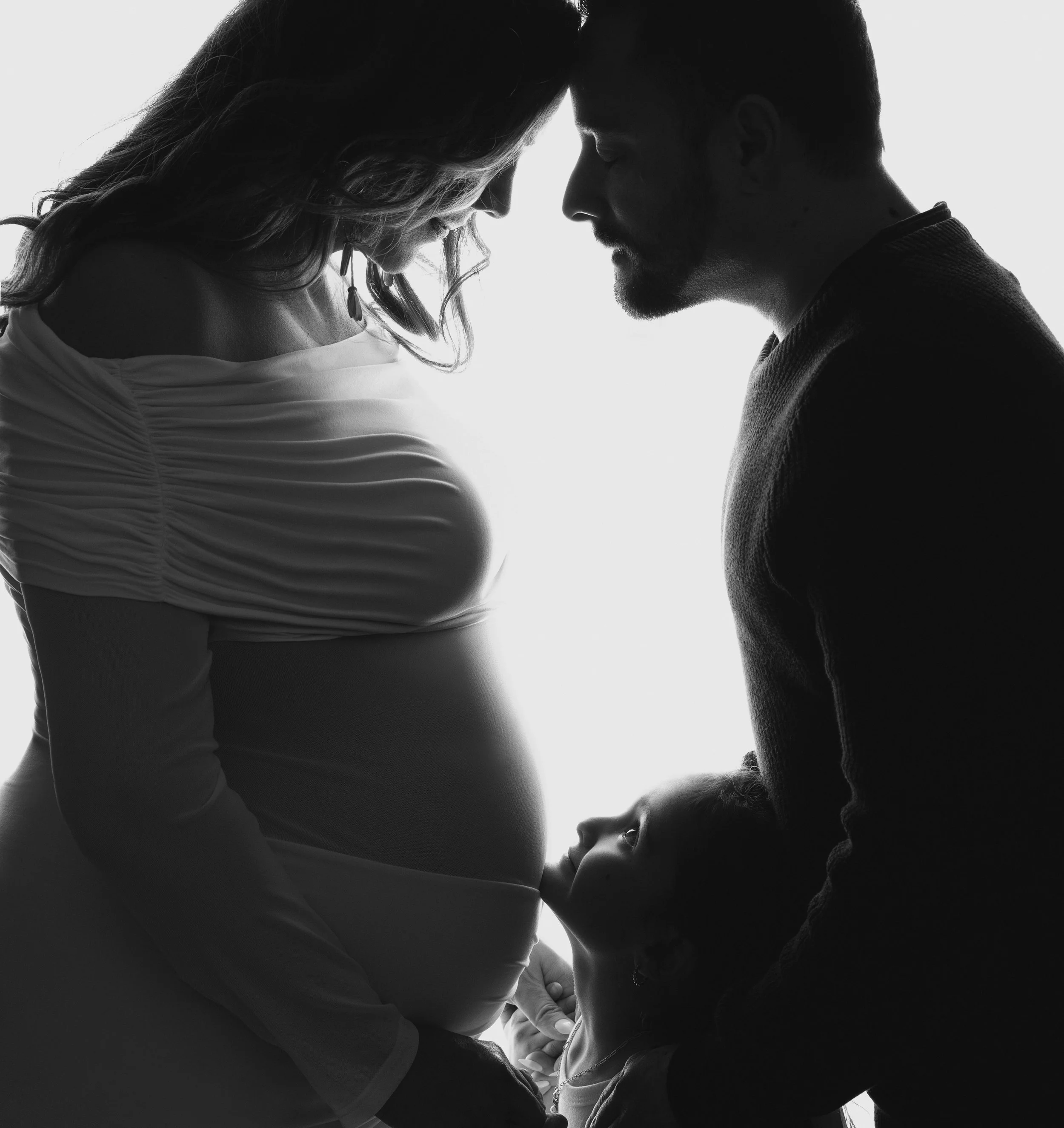 Pregnant mother, husband, and daughter sharing a tender moment during a Southern California maternity and family photography session serving the Inland Empire, Orange County, and Los Angeles County.