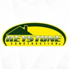 Keystone Construction logo featuring a yellow oval with a house silhouette and bold yellow and green text.