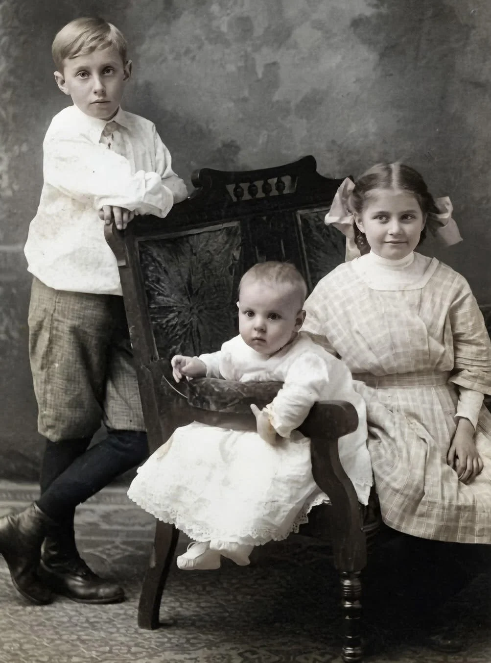 Old black and white photograph of three children, a school aged boy, a baby boy, and their middle sister. The girl is Jessica Howard's great-grandmother, and the two boys are her great-great uncles.