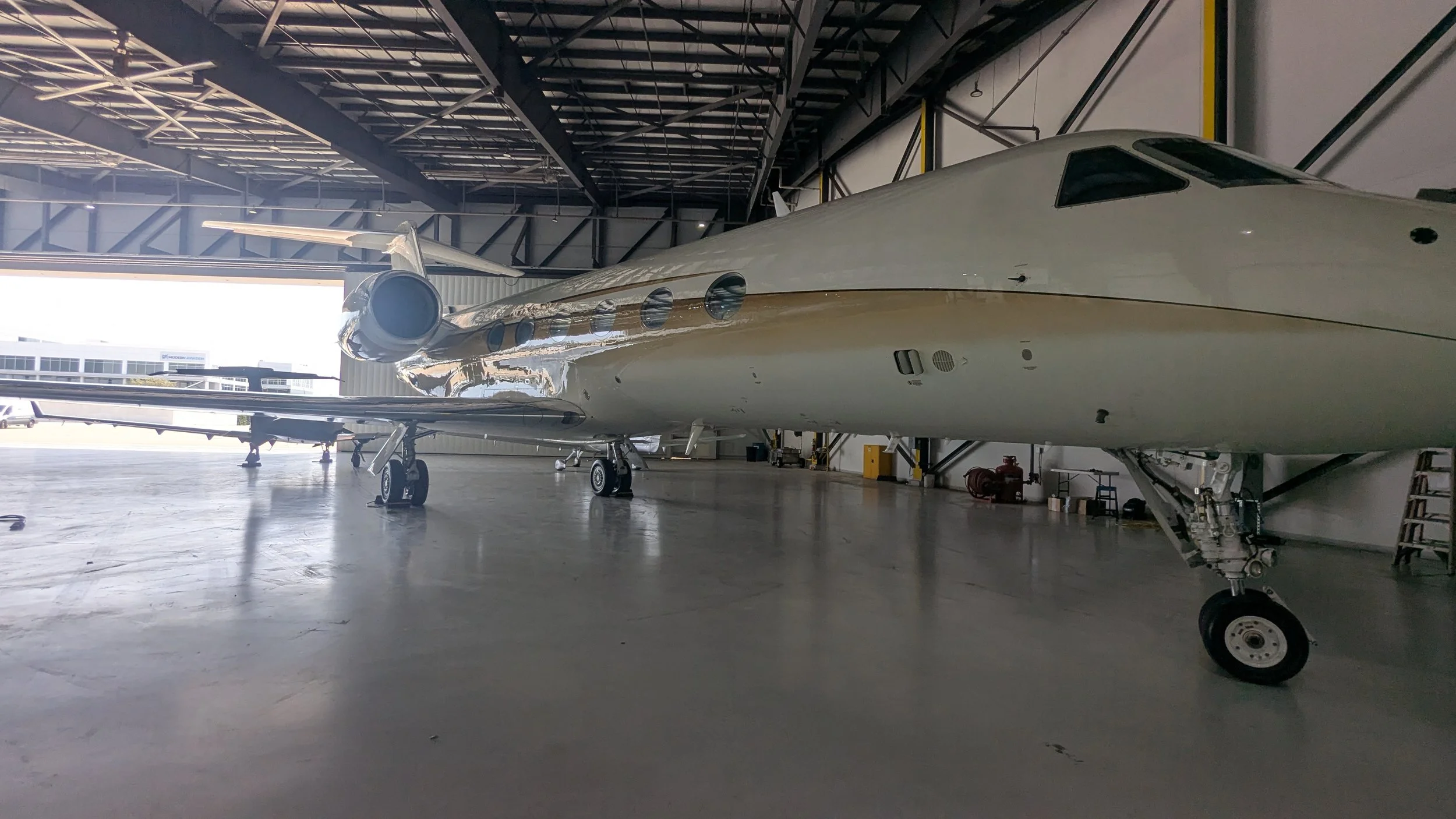Interior of an airplane hangar with a large private jet parked inside.