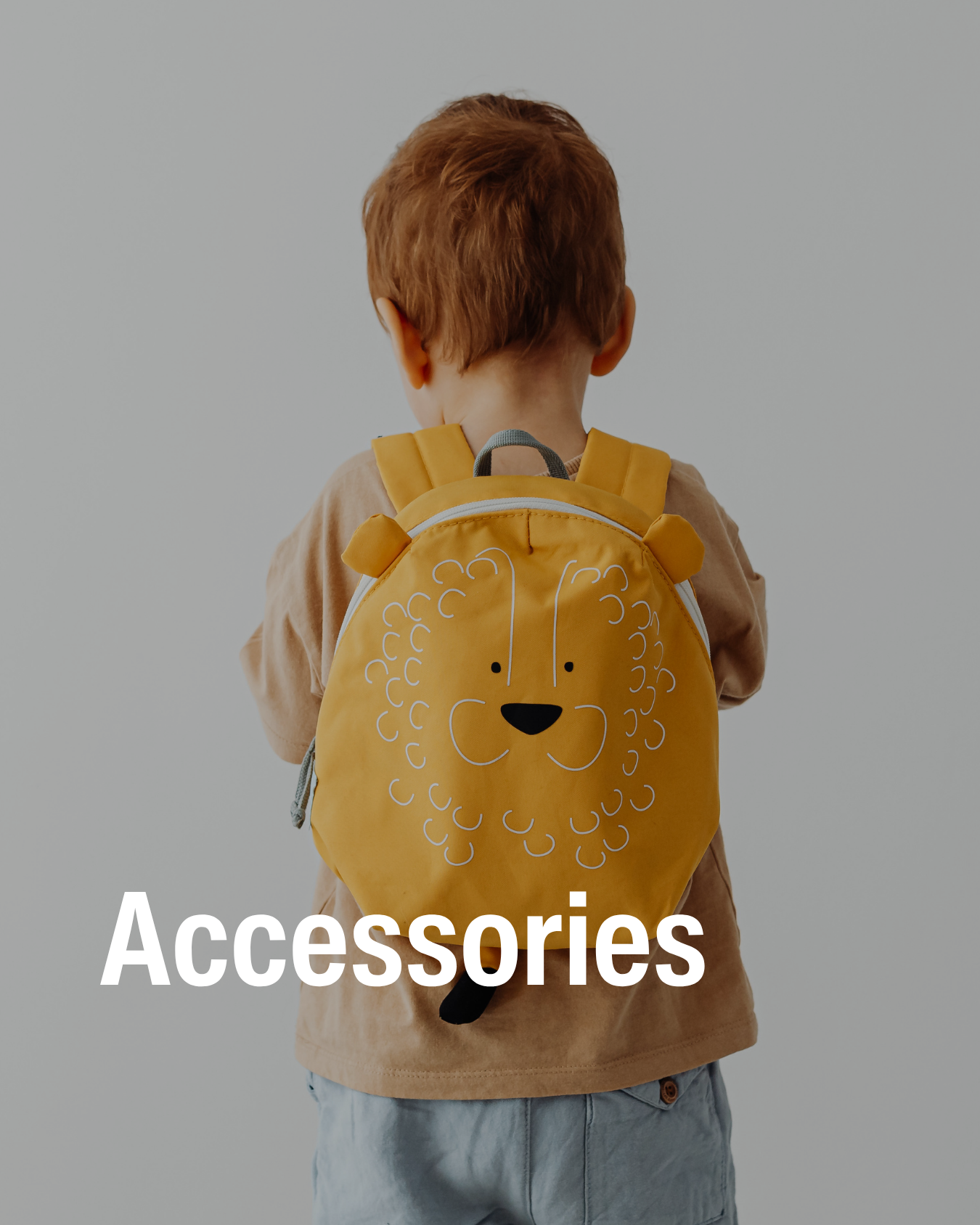 Young child with brown hair wears a yellow backpack showcasing the resale children accessories that chic kids sells.