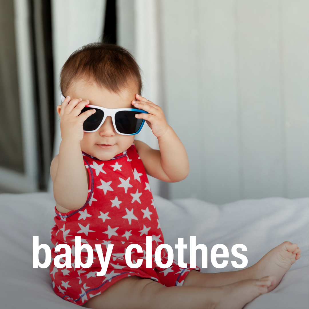 Baby in a red star-patterned outfit sits on a bed wearing white sunglasses from a kids consignment store, text reads “baby clothes.”.