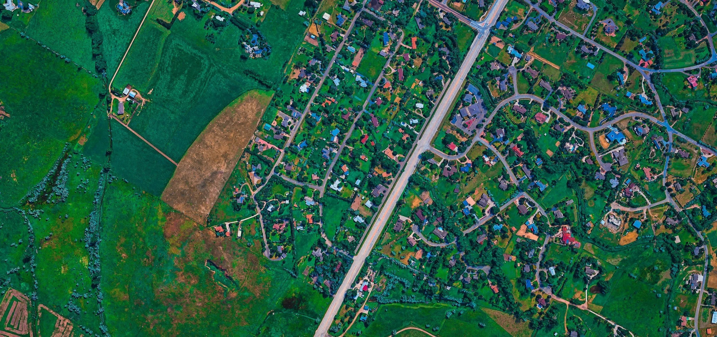 Aerial view of a suburban neighborhood with houses, roads, and green spaces.