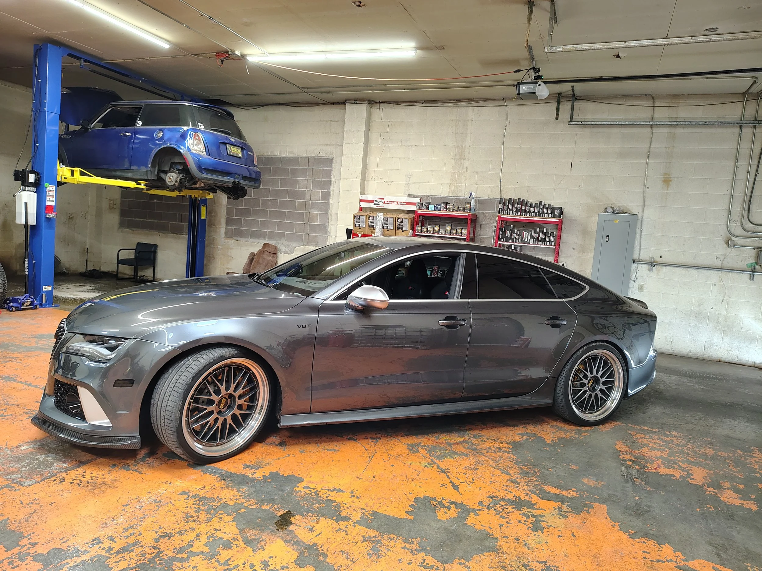 A gray sports car parked inside an automotive garage.