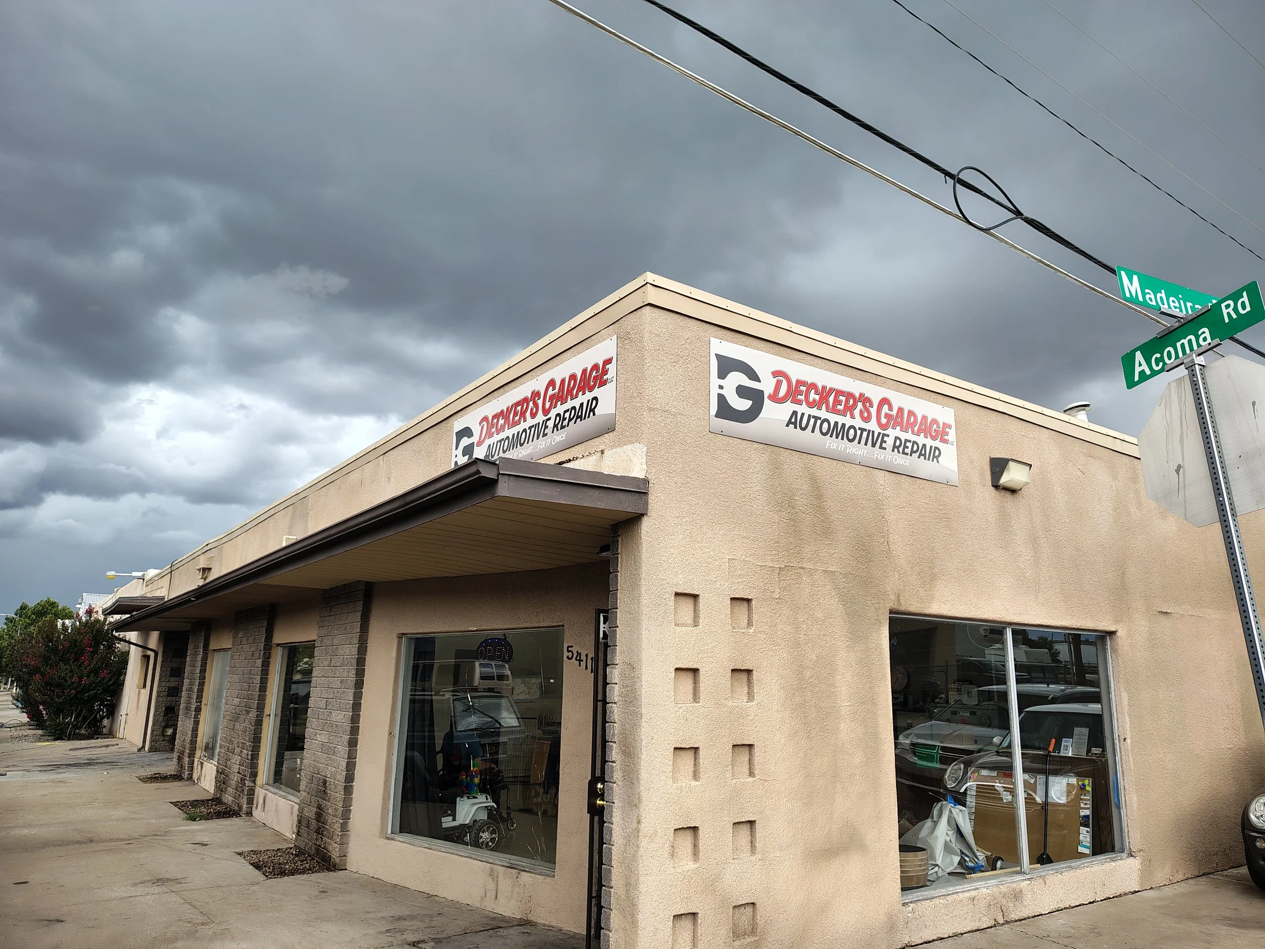 The exterior of an automotive repair shop called Decker's Garage, located on the corner of Madeiras Road and Acoma Road, with dark overcast skies overhead.