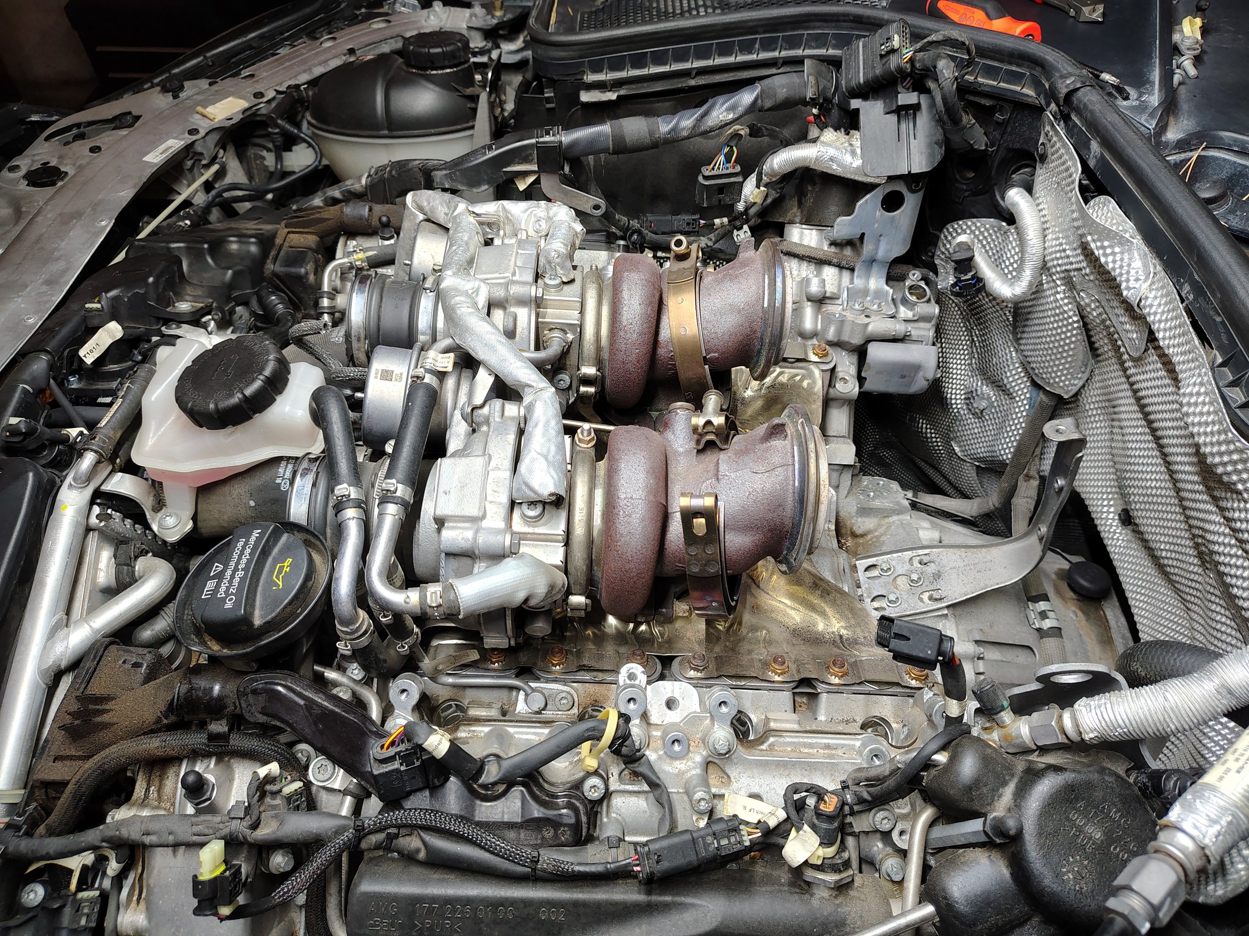 Close-up view of a car engine with various components, hoses, and wiring visible.