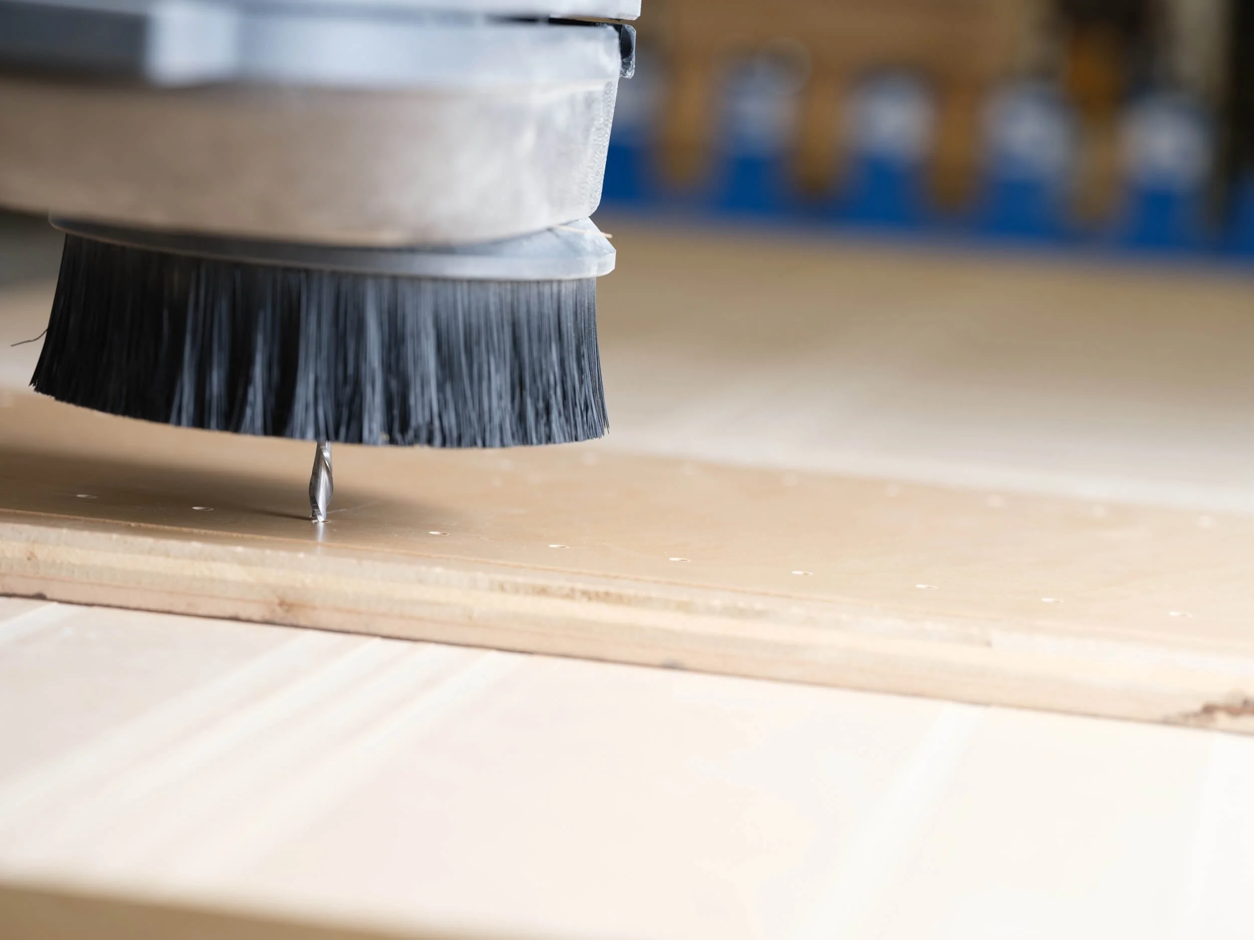 Close-up of a nail drill pressing down on a piece of wood, used for carpentry or woodwork.